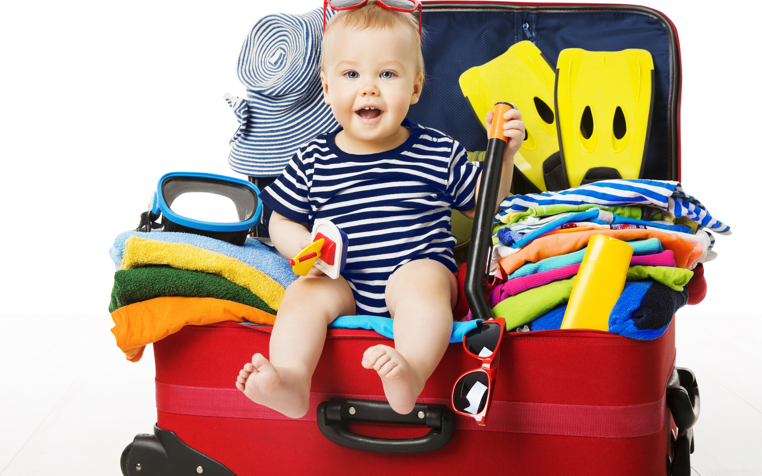 Маленький ребенок сидит в большом красном чемодане с вещами