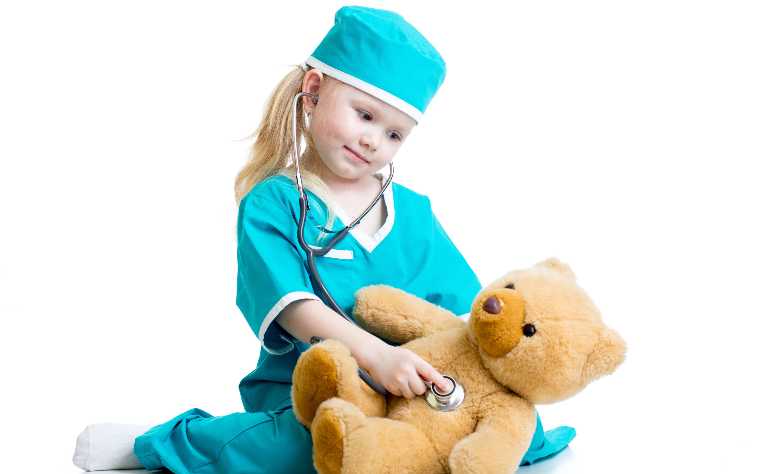 Маленькая девочка в костюме врача лечит плюшевого медвежонка
