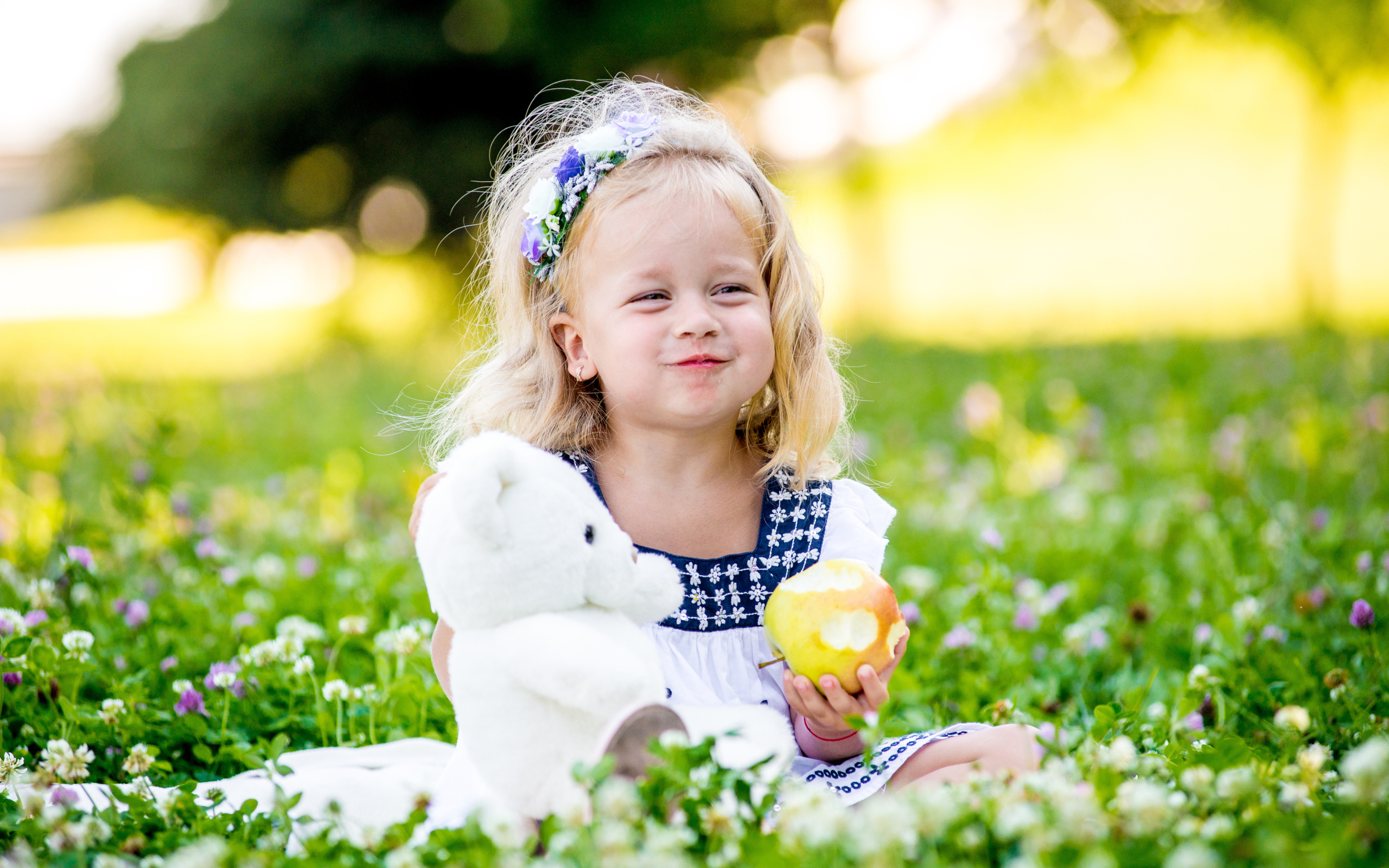 Маленькая девочка с белым медвежонком в руках и большим яблоком