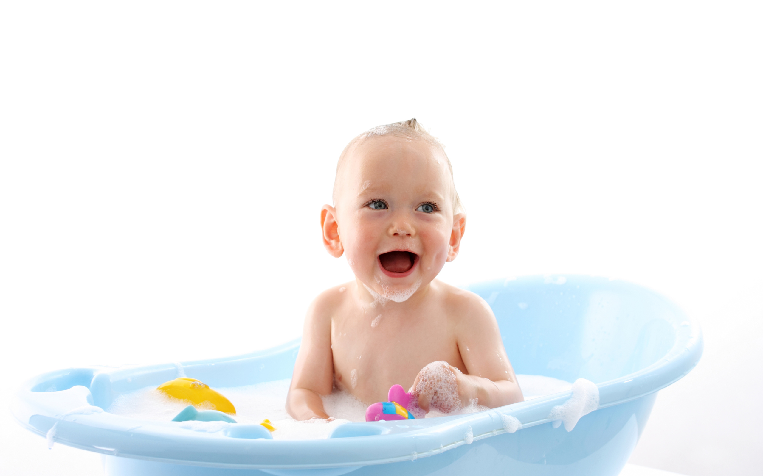 Улыбающийся грудной ребенок сидит в синей ванночке на белом фоне