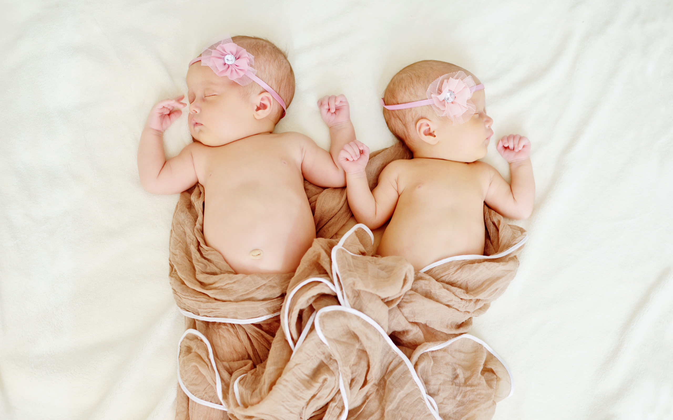 Два спящих младенца с розовыми цветами на голове