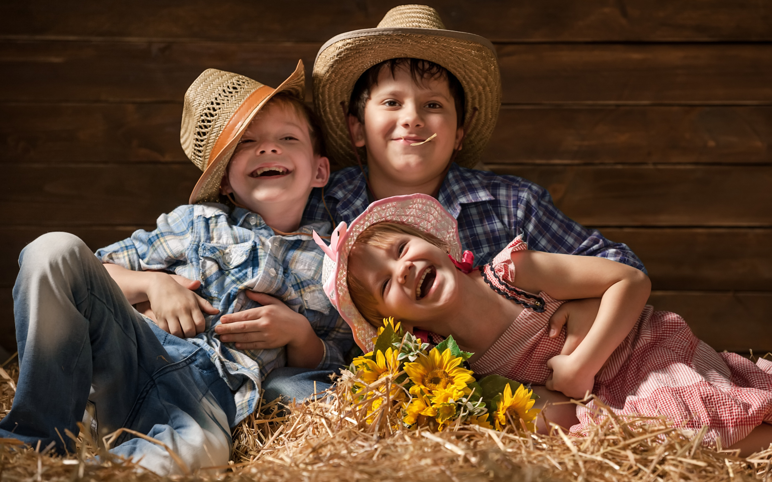Два улыбающихся мальчика и девочка в соломенных  шляпах