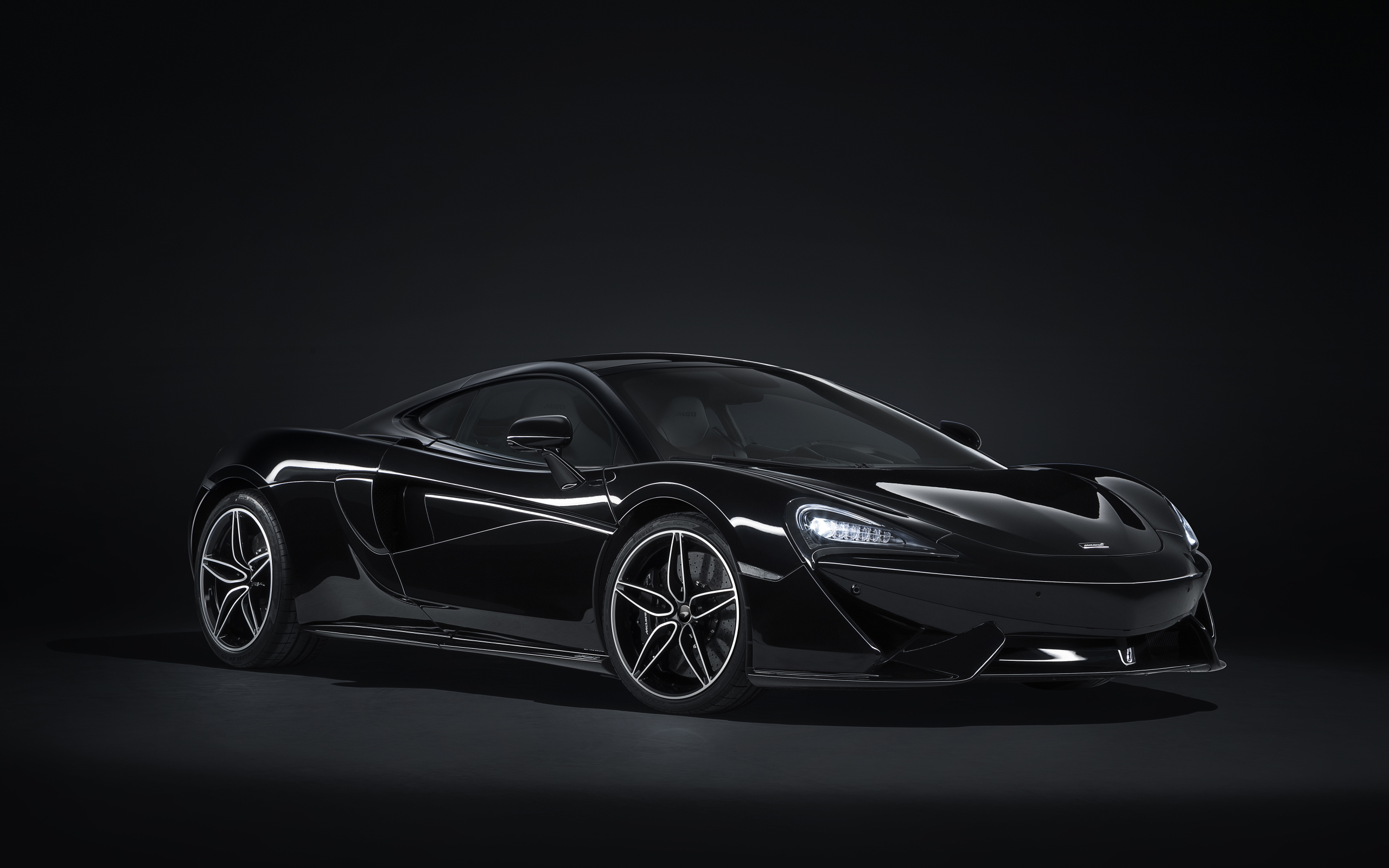 Черный спортивный автомобиль McLaren 570GT на сером фоне