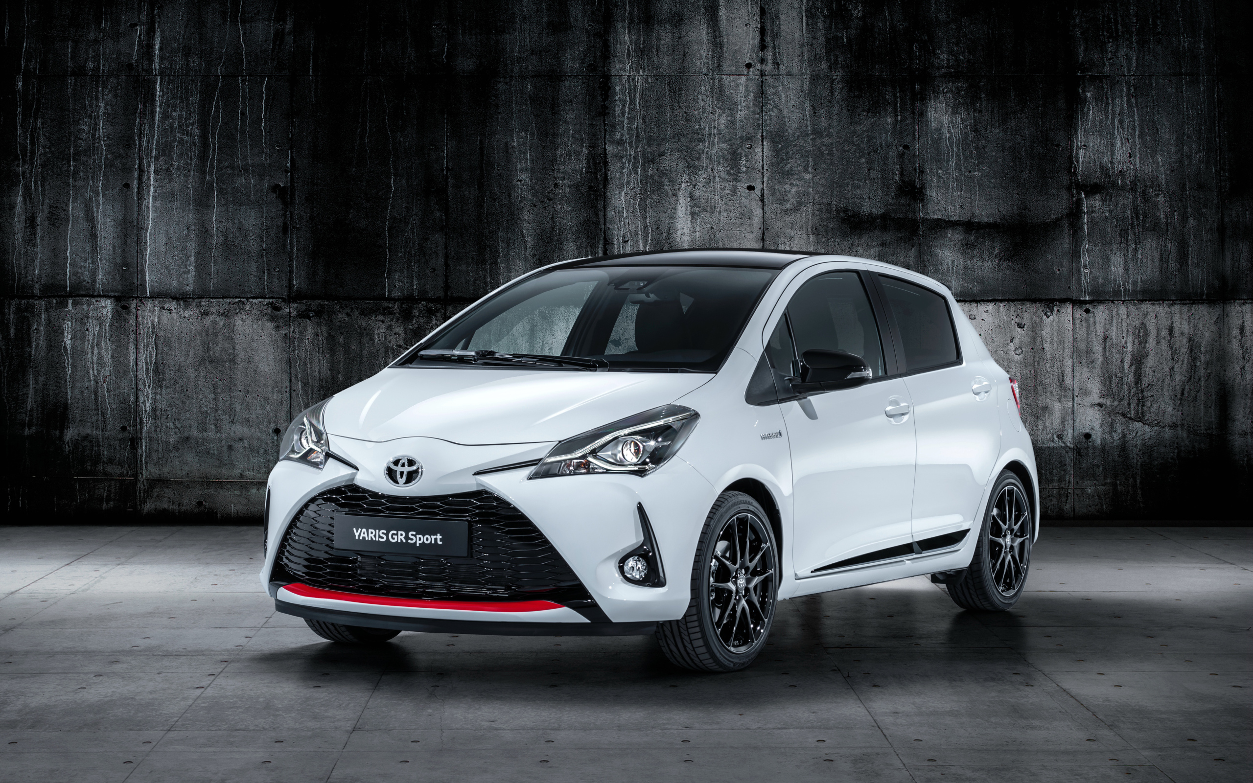 Белый автомобиль Toyota Yaris на сером фоне 