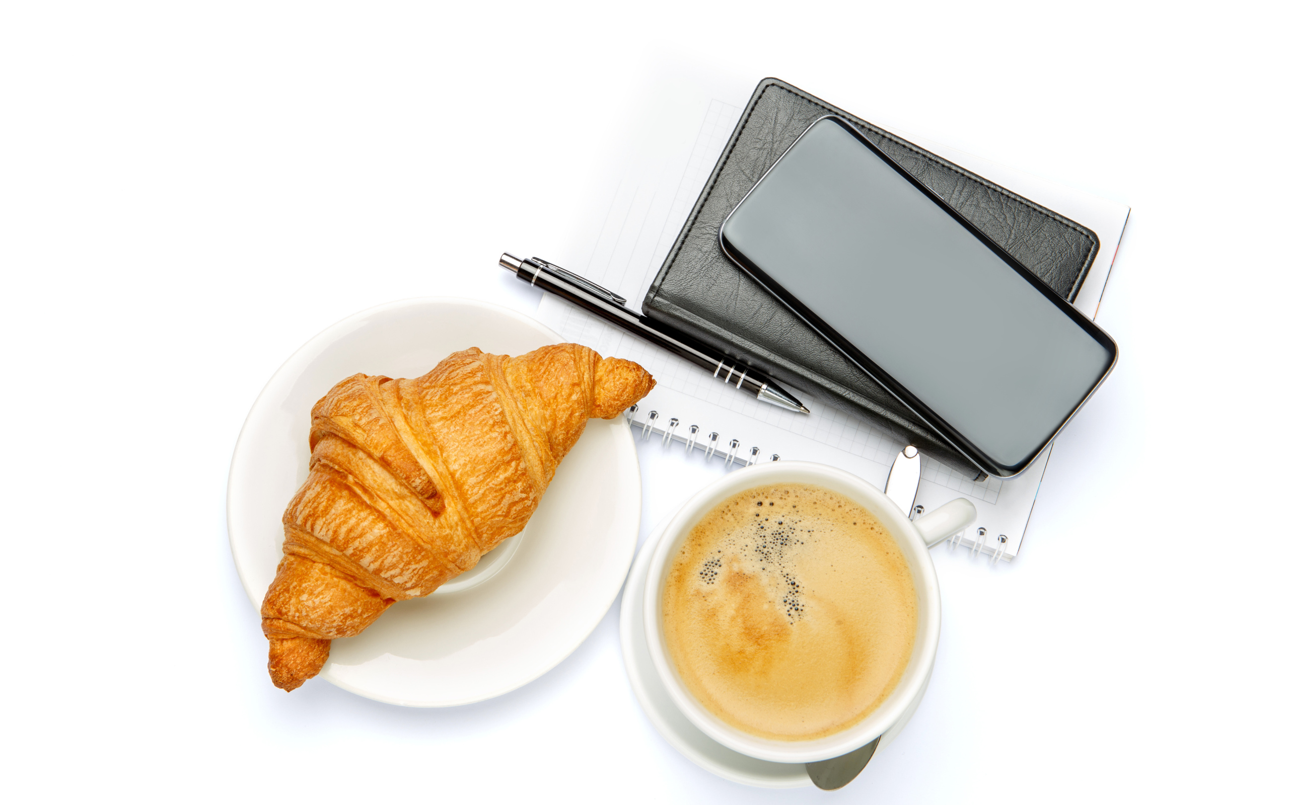 Чашка кофе, круассан, блонтон и смартфон на белом 