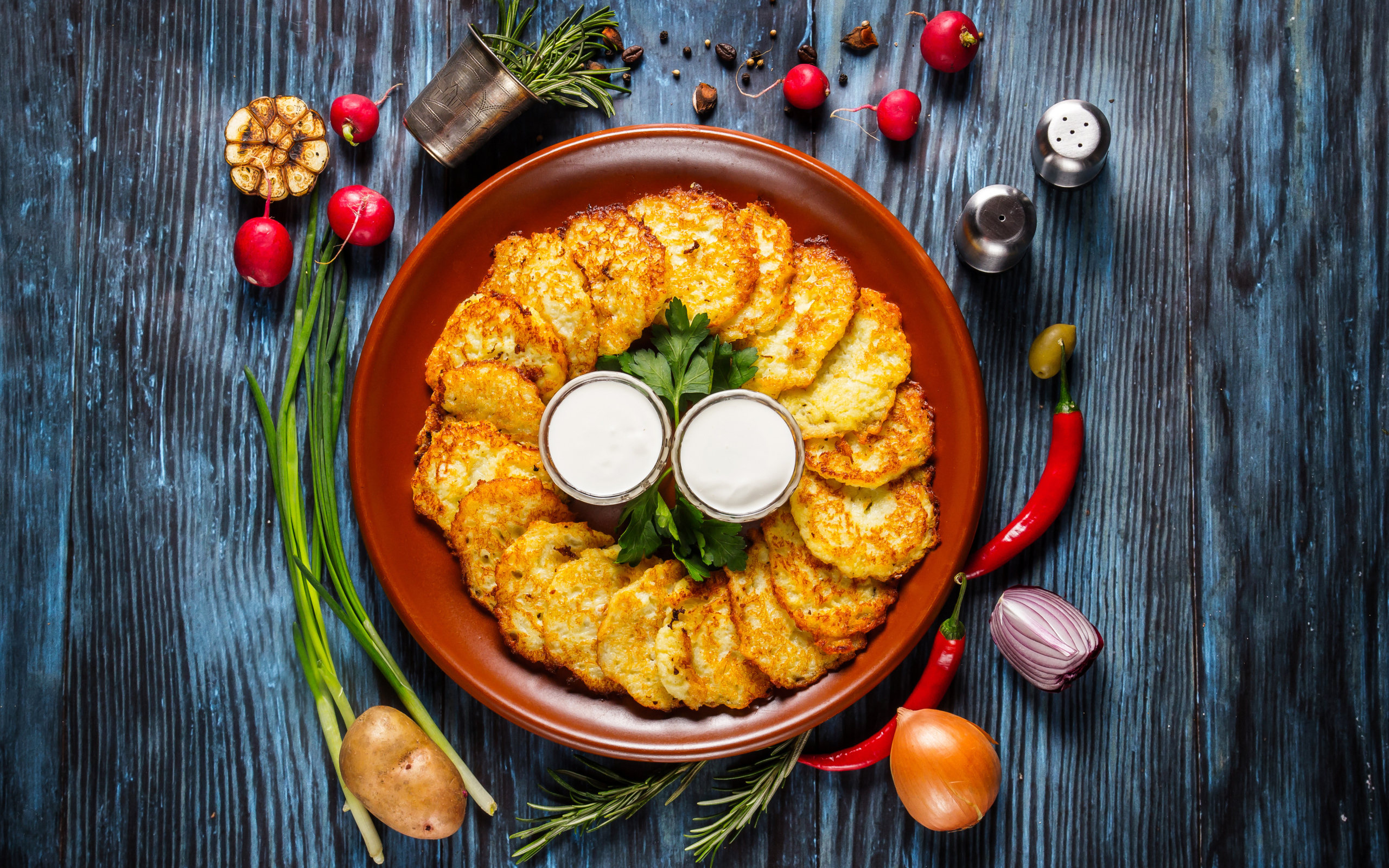 Драники с соусом на тарелке на столе с овощами