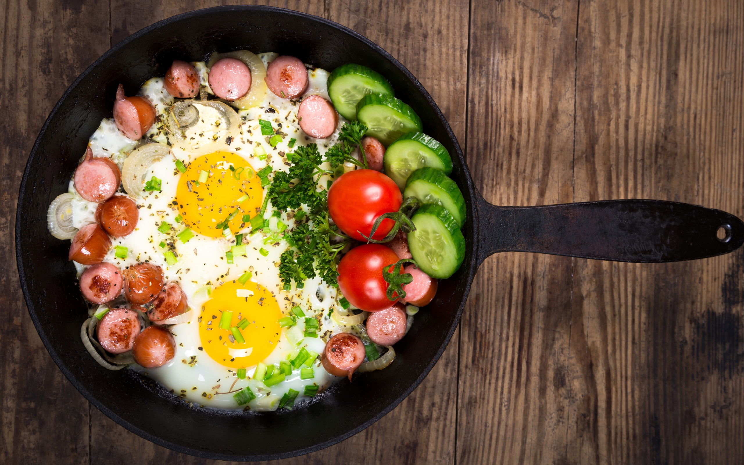 Яичница в сковороде с овощами и кусочками сосиски