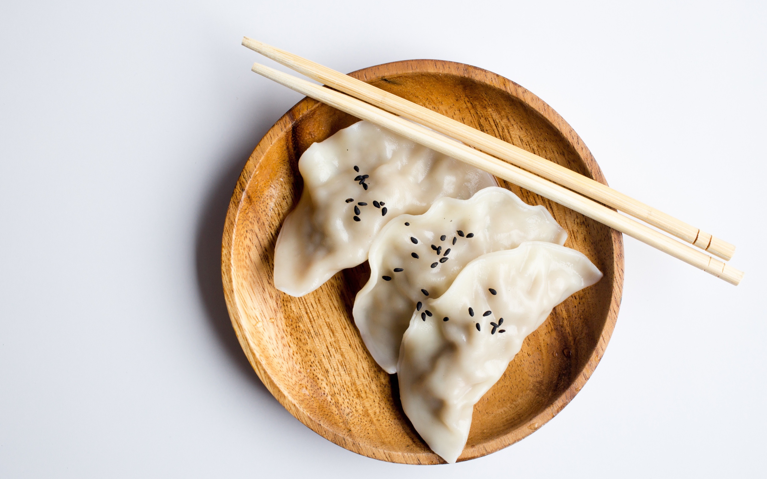 Три вареника на деревянной тарелке с палочками