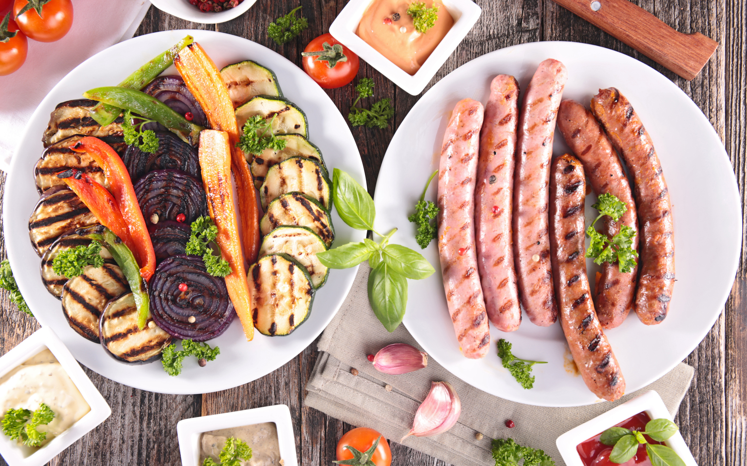 Овощи и сосиски гриль на столе с соусом