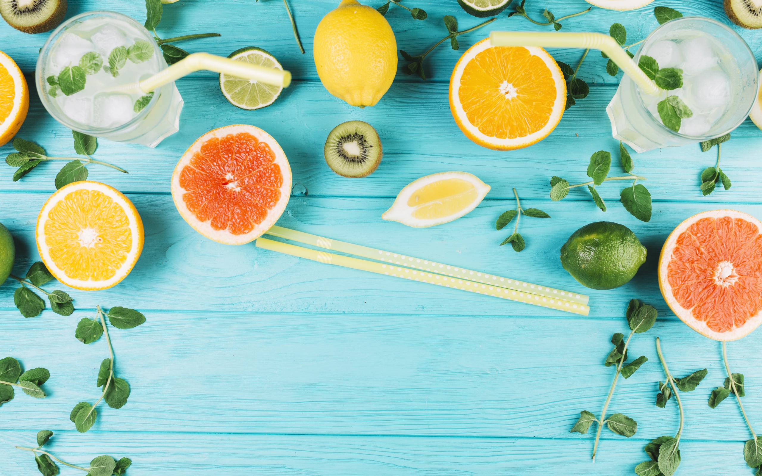 Цитрусовые фрукты на голубом столе с мятой и лимонадом