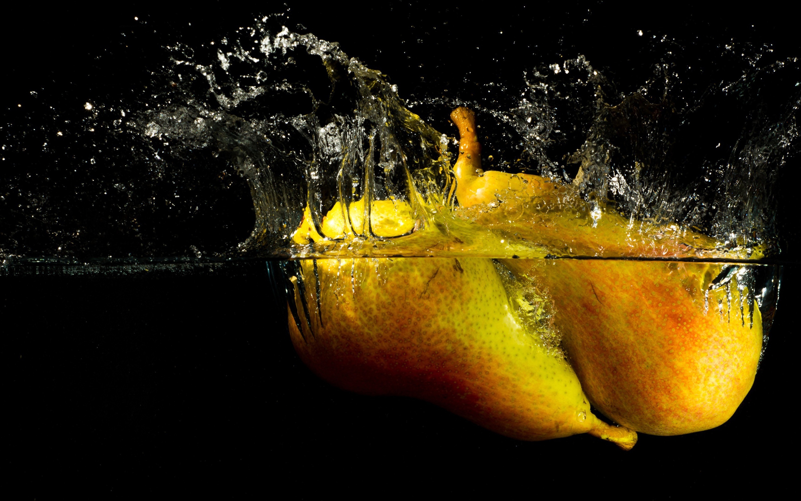 Груши в воде с брызгами на черном фоне