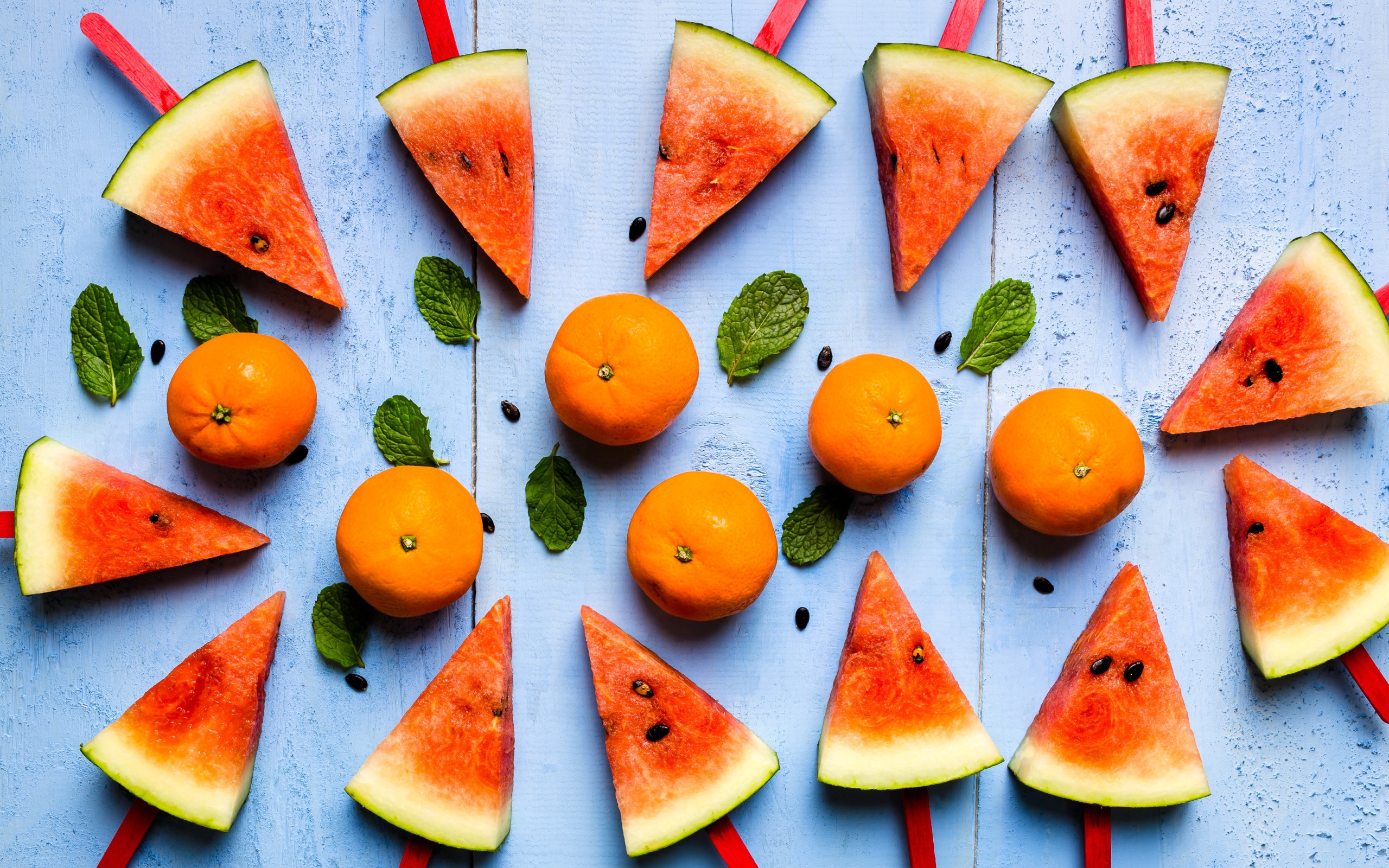 Кусочки арбуза на палочках на столе с мандаринами