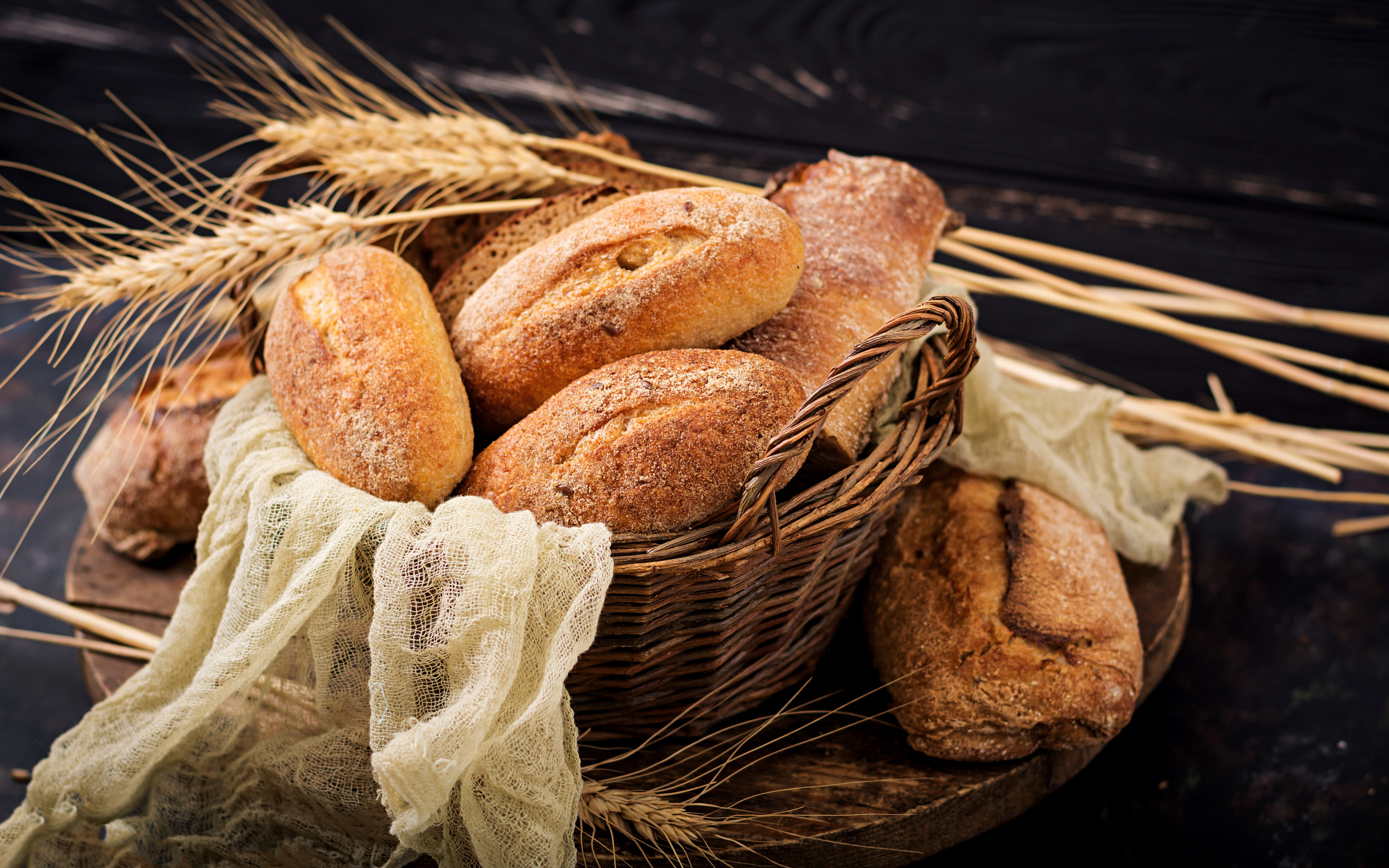 Свежая выпечка в корзине на столе с колосьями пшеницы