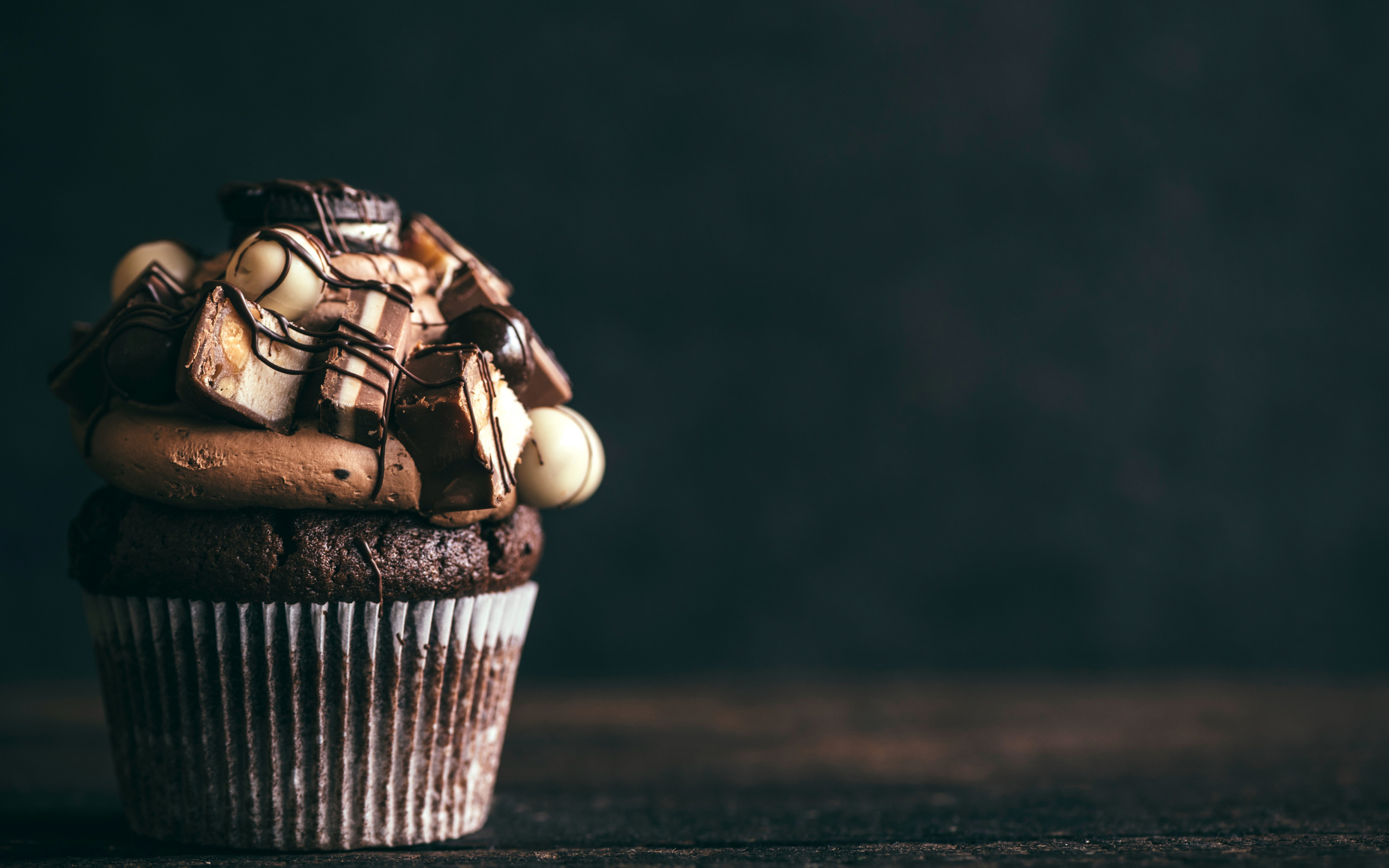 Шоколадный кекс с кремом и конфетами на сером фоне