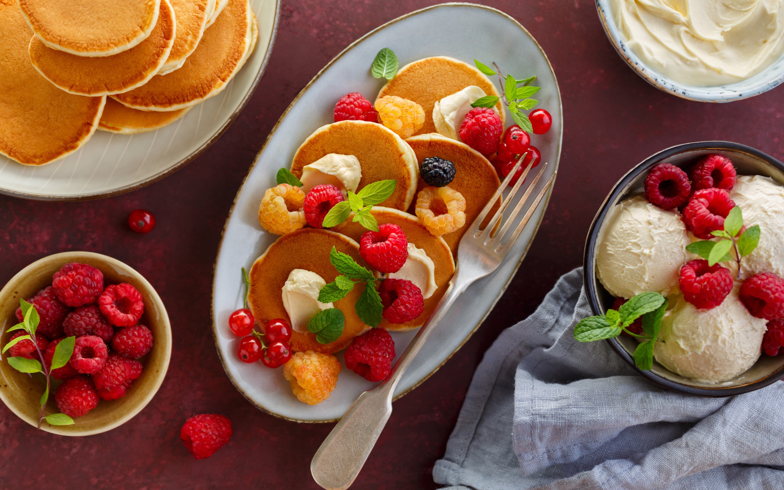 Оладьи на столе с ягодами малины и мороженым