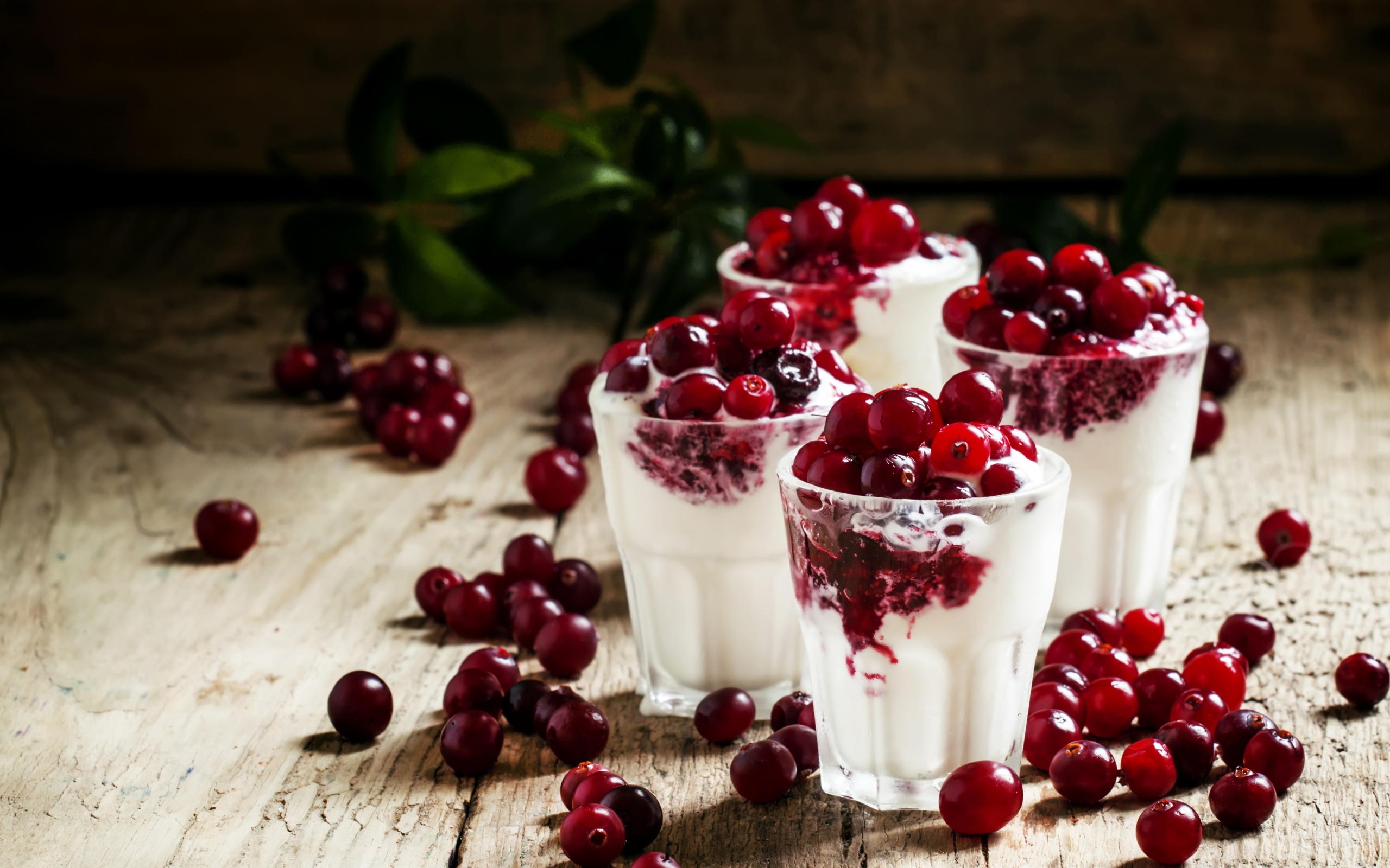 Сладкий десерт с клюквой в стеклянных стаканах