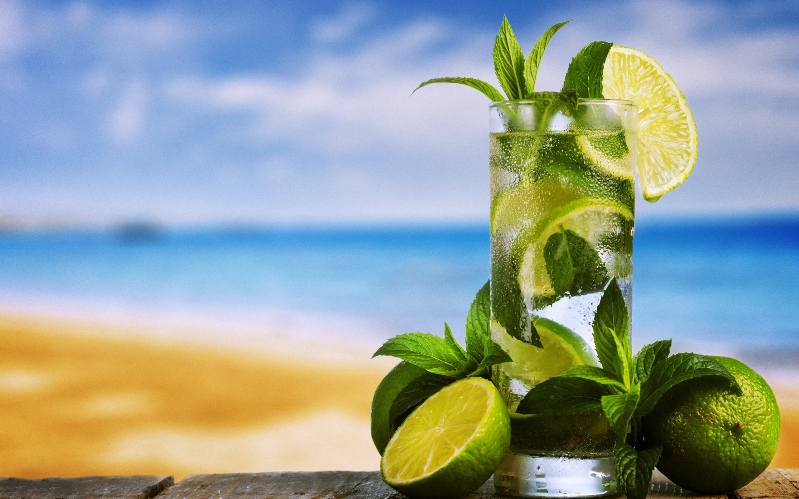 Стакан холодного мохито на столе с мятой и лаймом