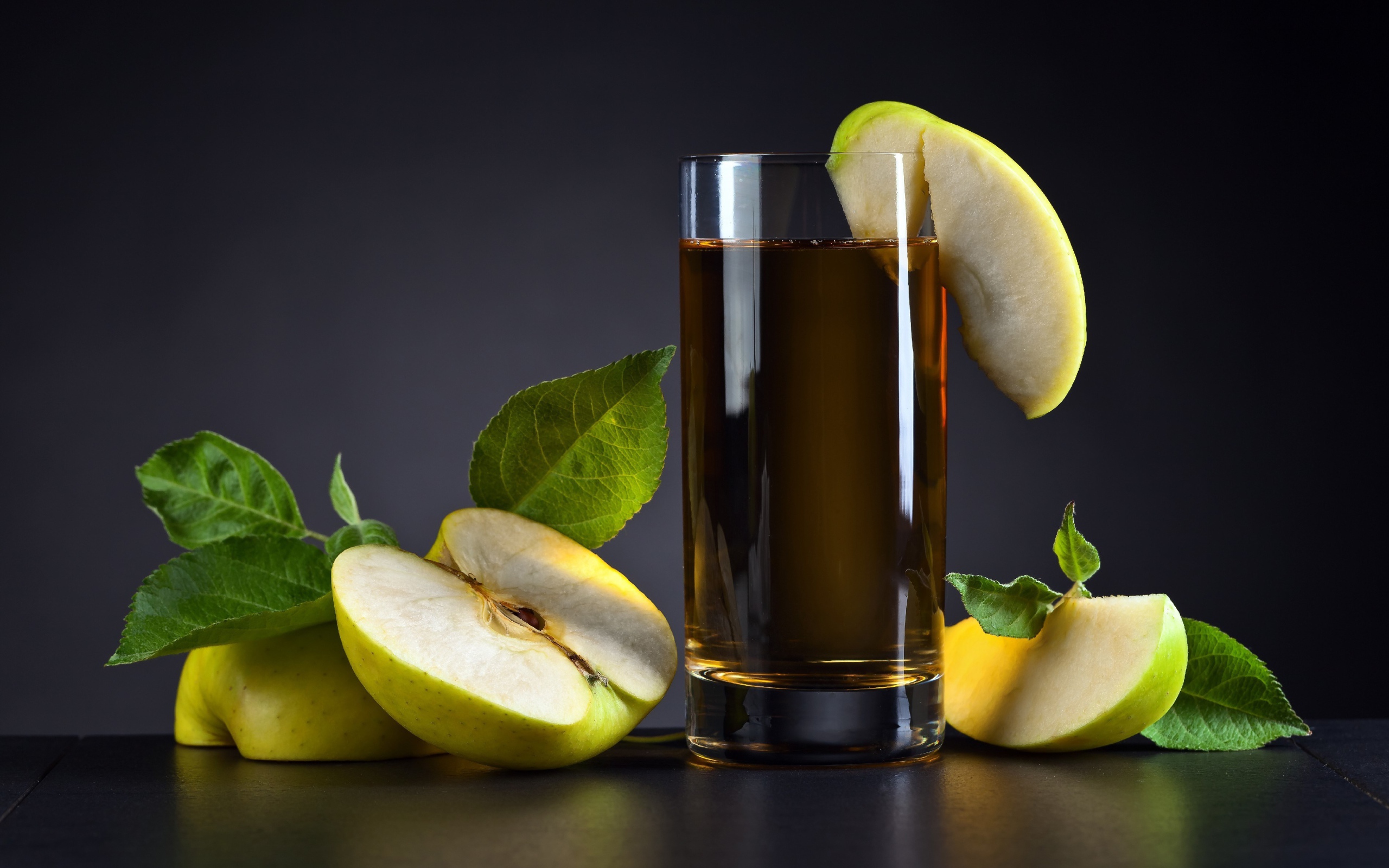 Яблочный сок в стакане на столе со свежими яблоками на сером фоне