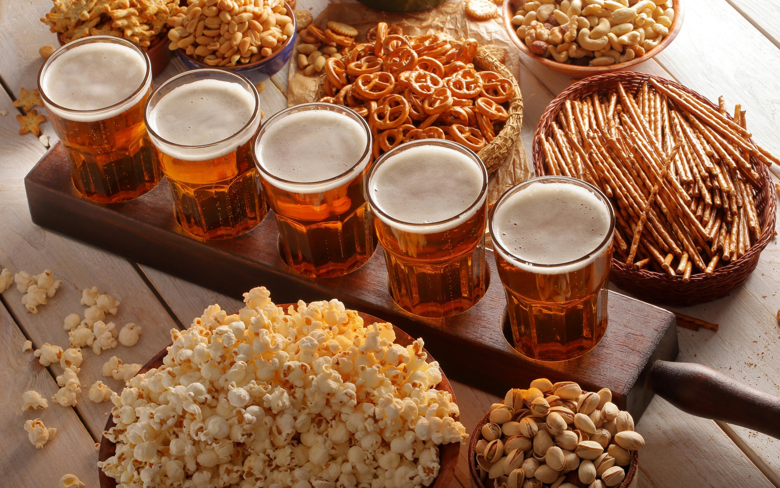 Пиво с орешками, фисташками, попкорном и печеньем на столе