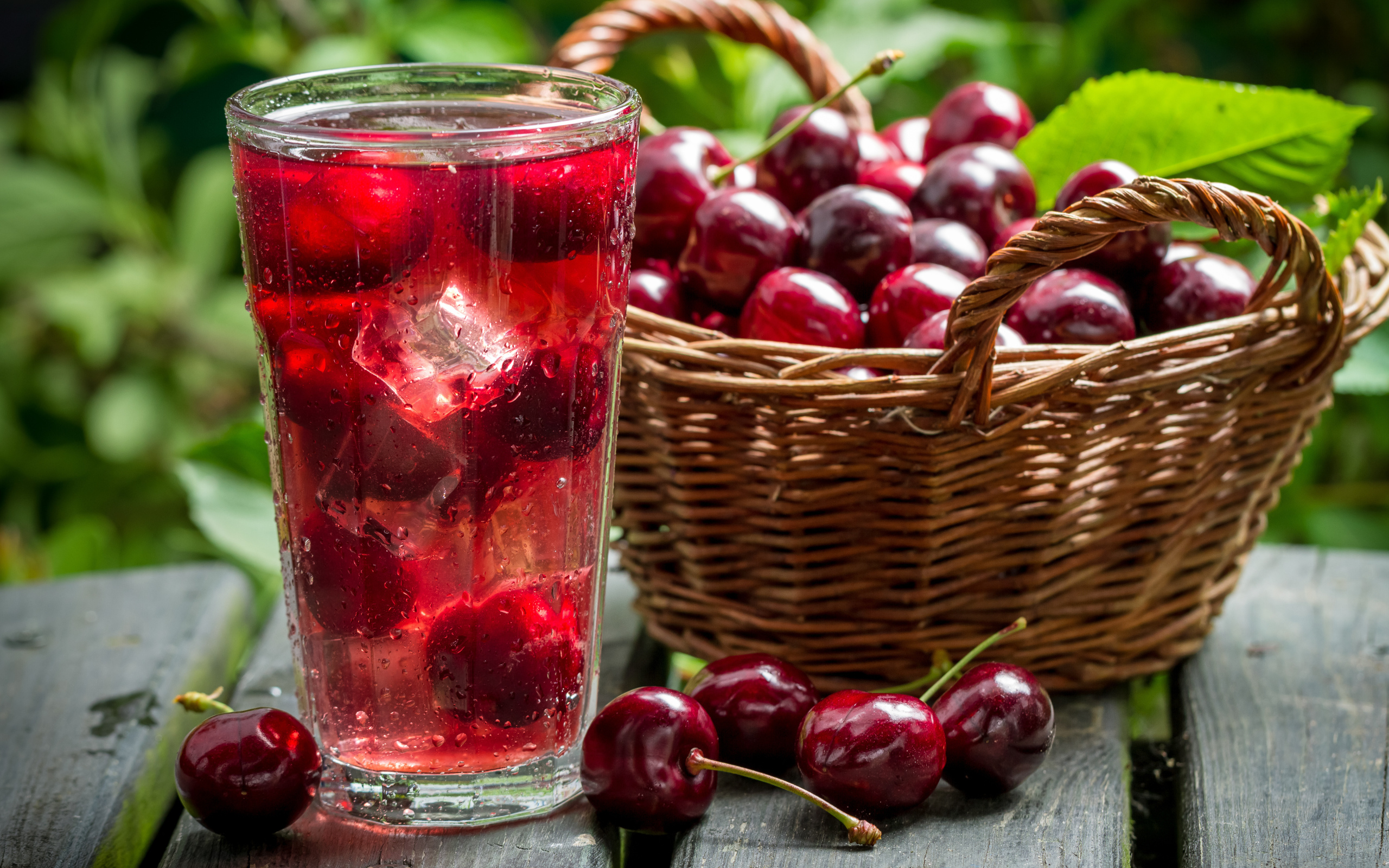Стакан напитка со льдом на столе с корзиной с черешней 