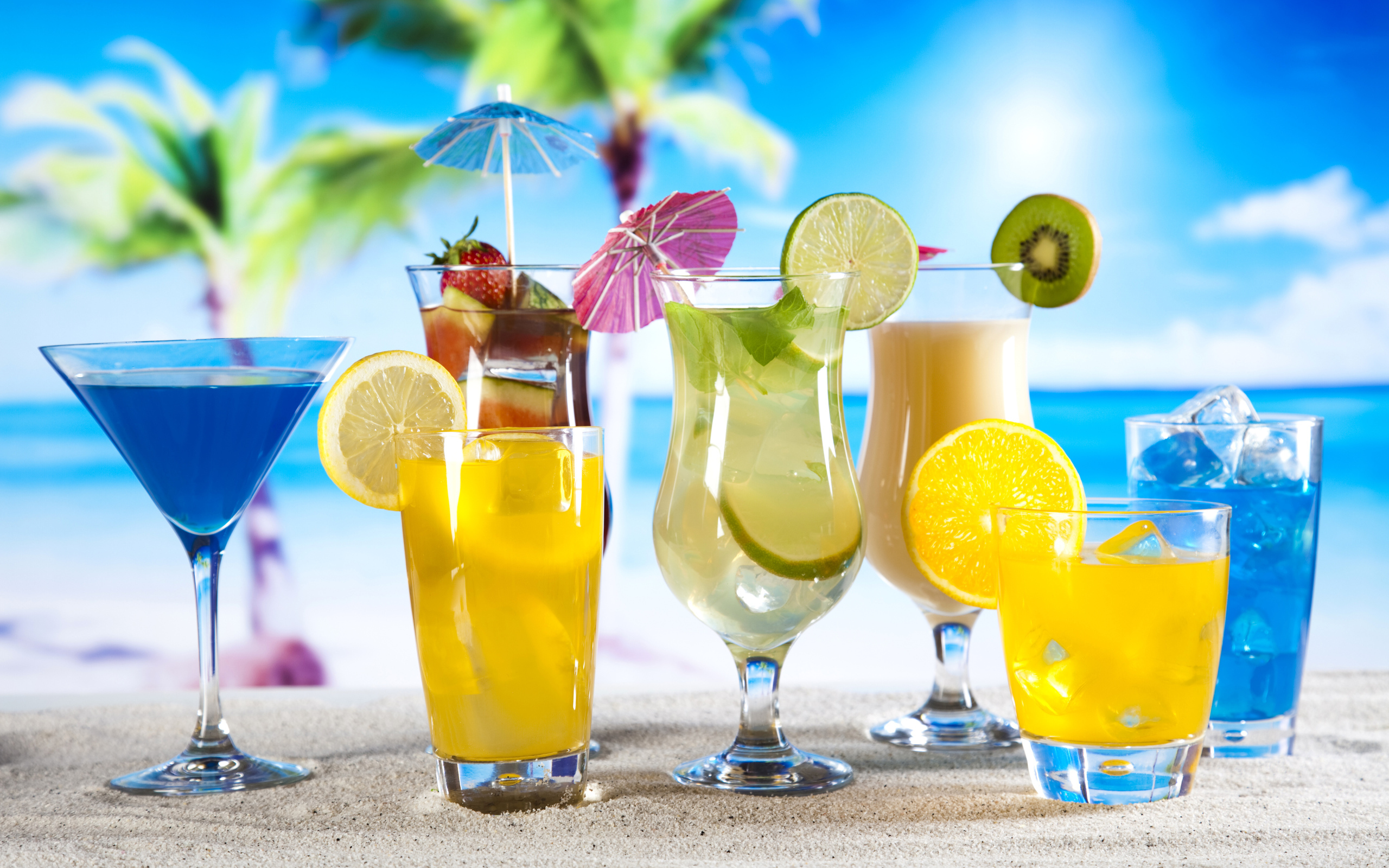 Бокалы с тропическими коктейлями на песке на пляже