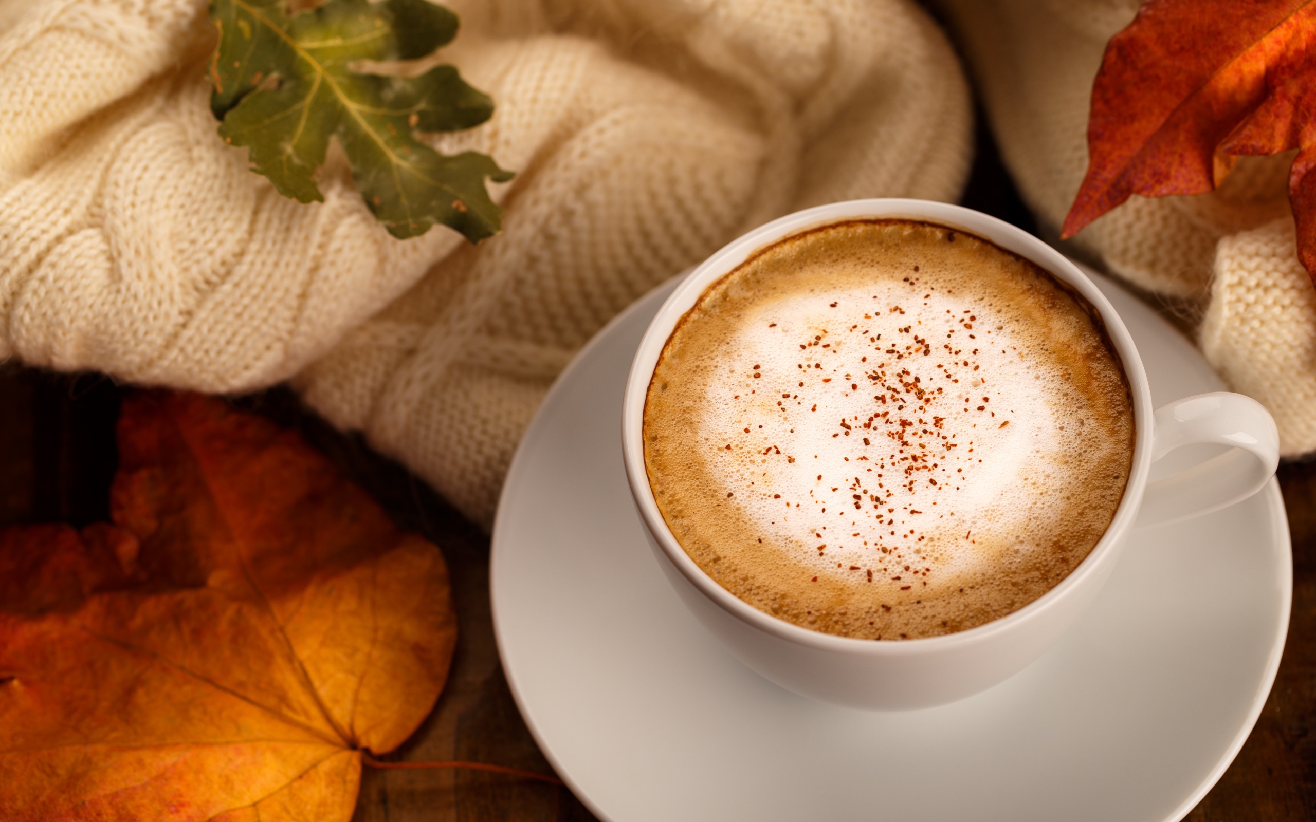 Белая чашка с вкусным кофе на столе с желтыми листьями