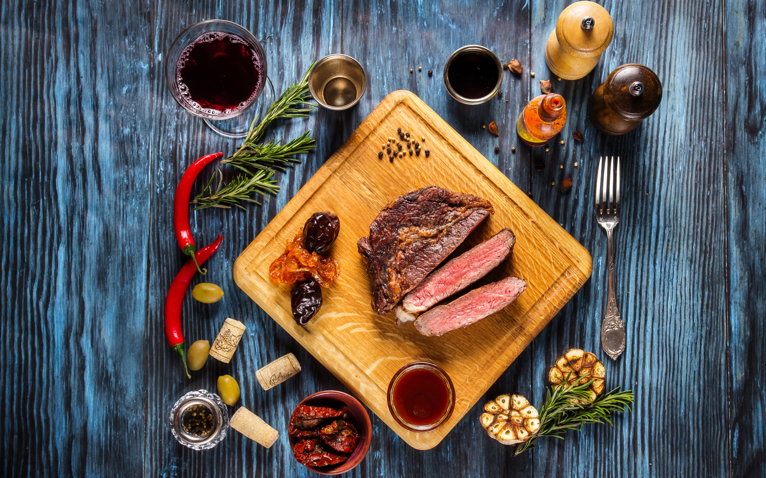 Кусок мяса на столе со специями и стаканом вина