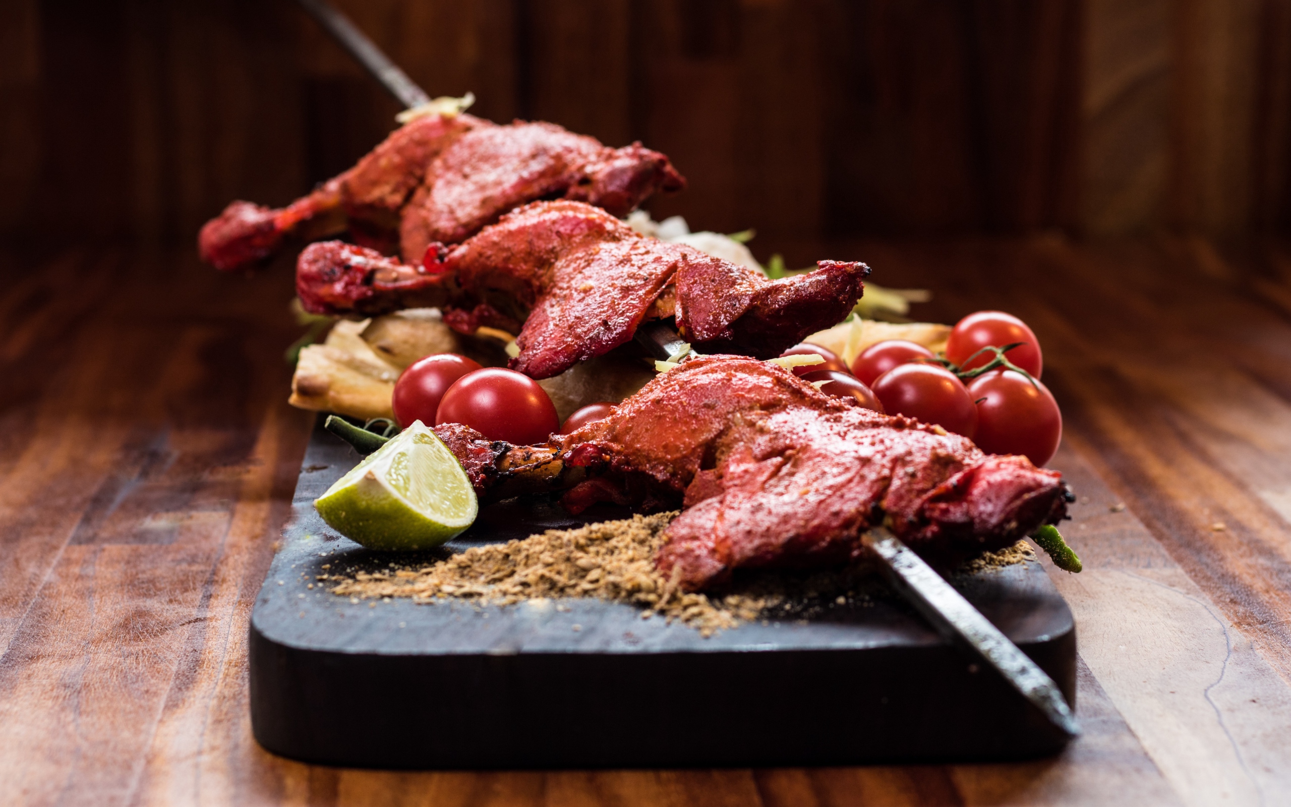 Курица жареная на шампурах на столе с овощами 