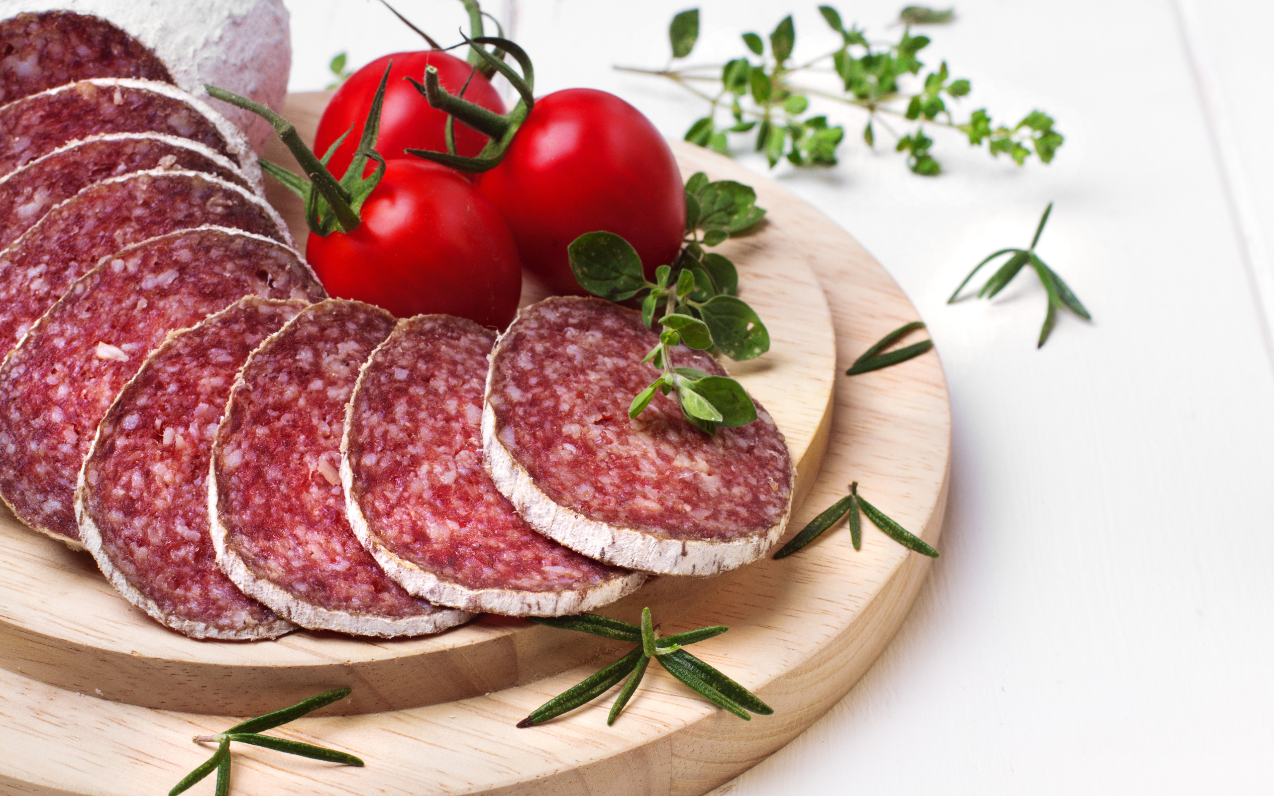 Вкусная колбаса на разделочной доске с помидорами и зеленью 