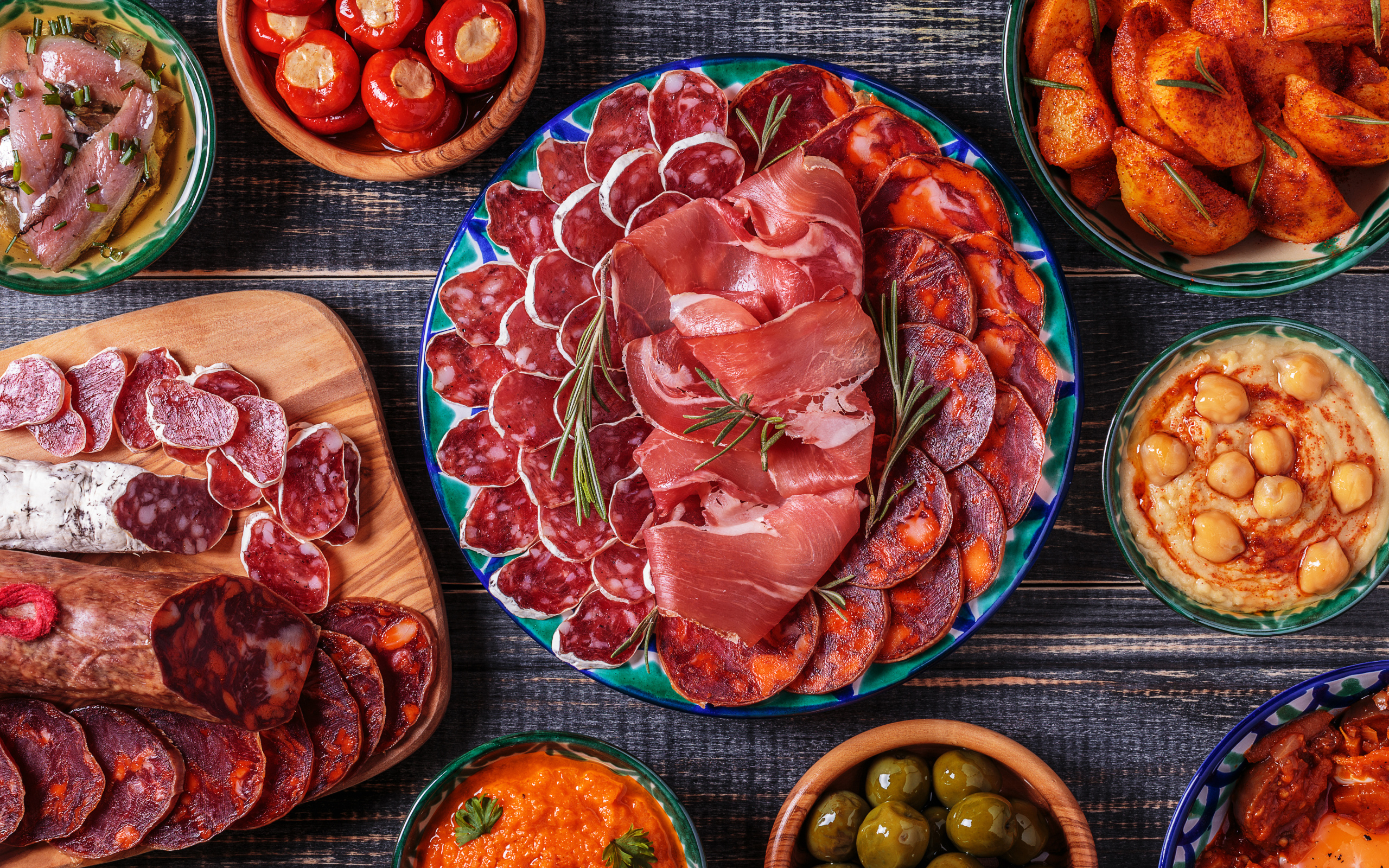 Большая тарелка с мясной нарезкой в центре праздничного стола