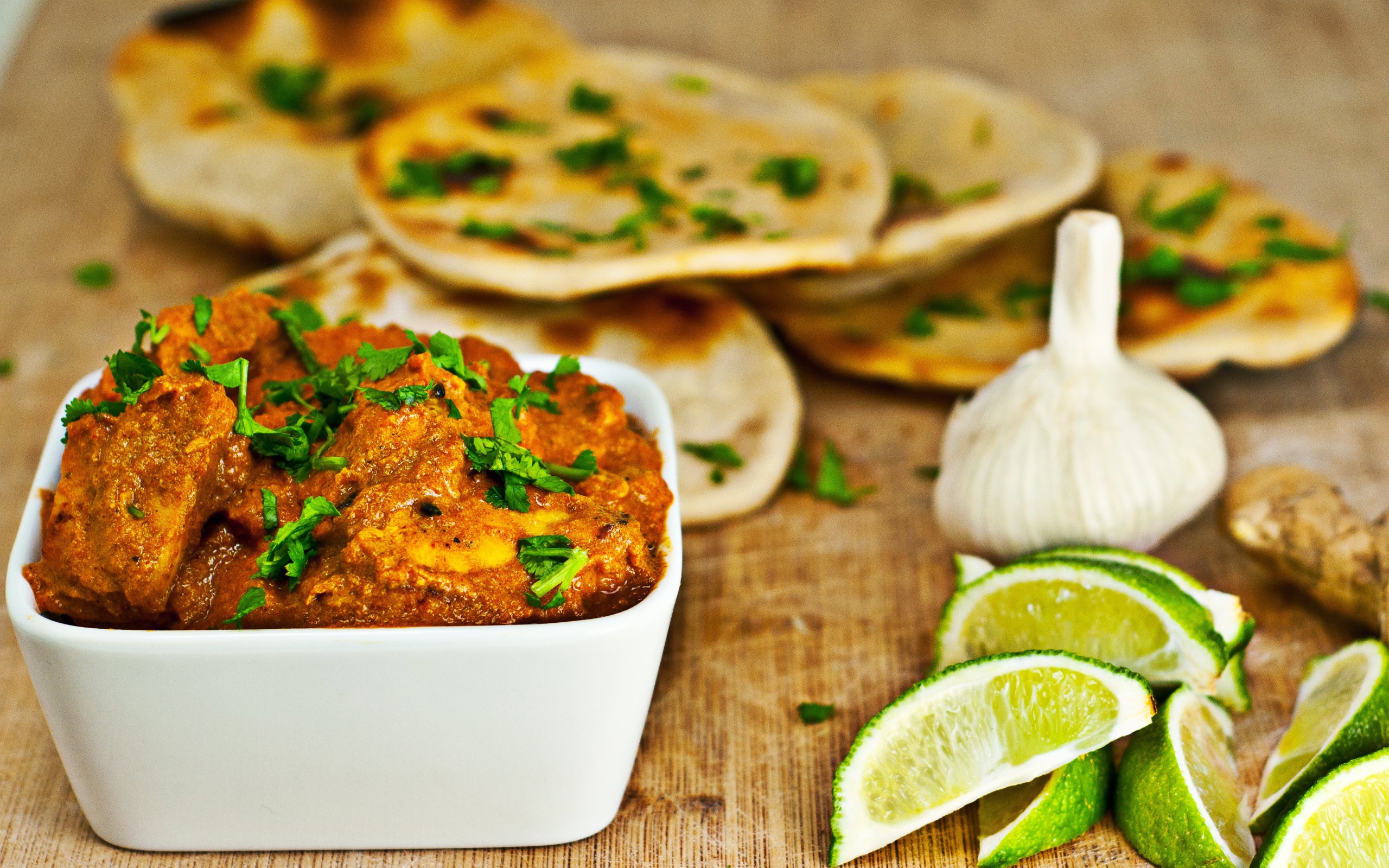 Мясное блюдо на столе с лепешками, кусочками лайма и чесноком