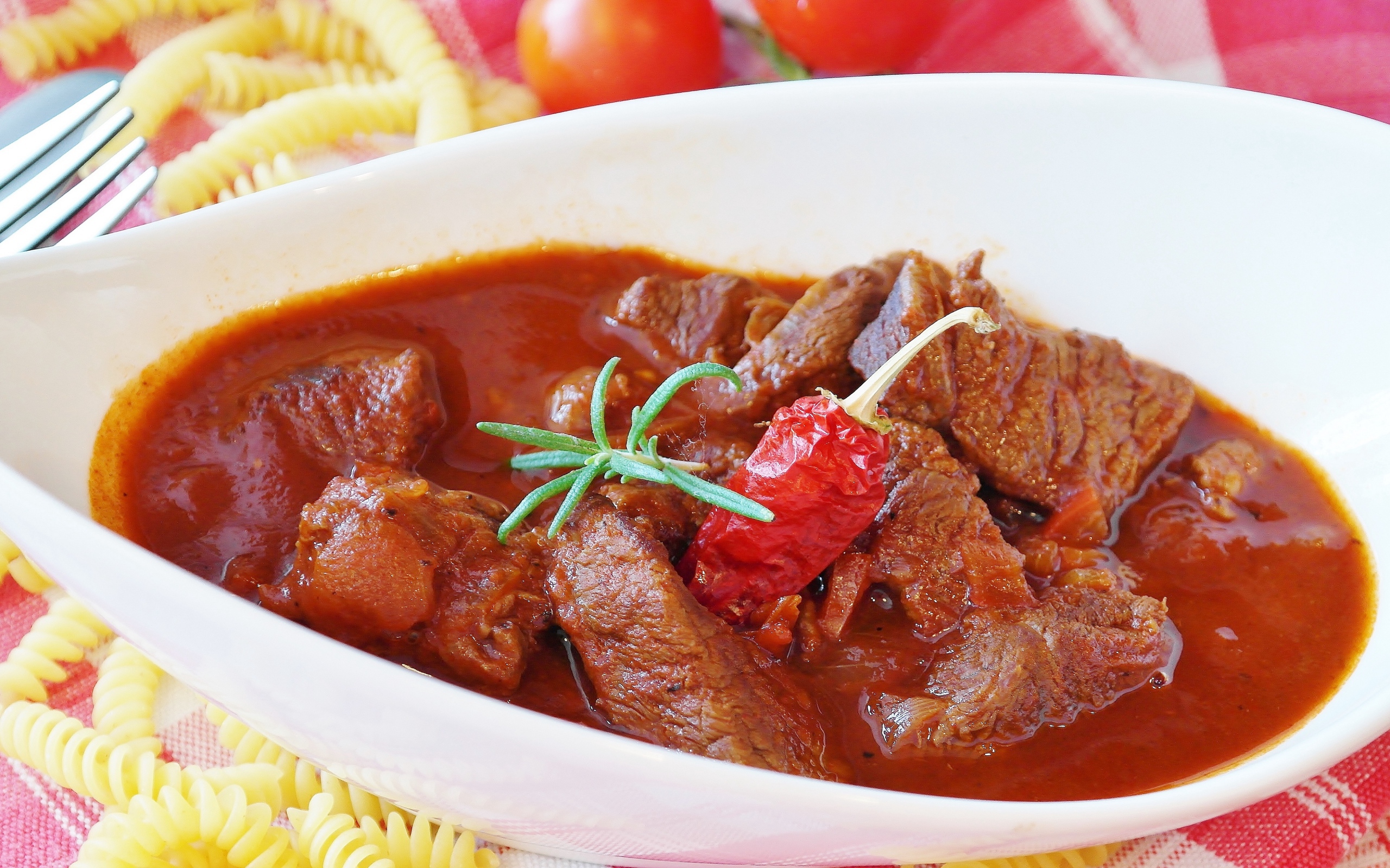 Мясной гуляш в белой тарелке с острым перцем