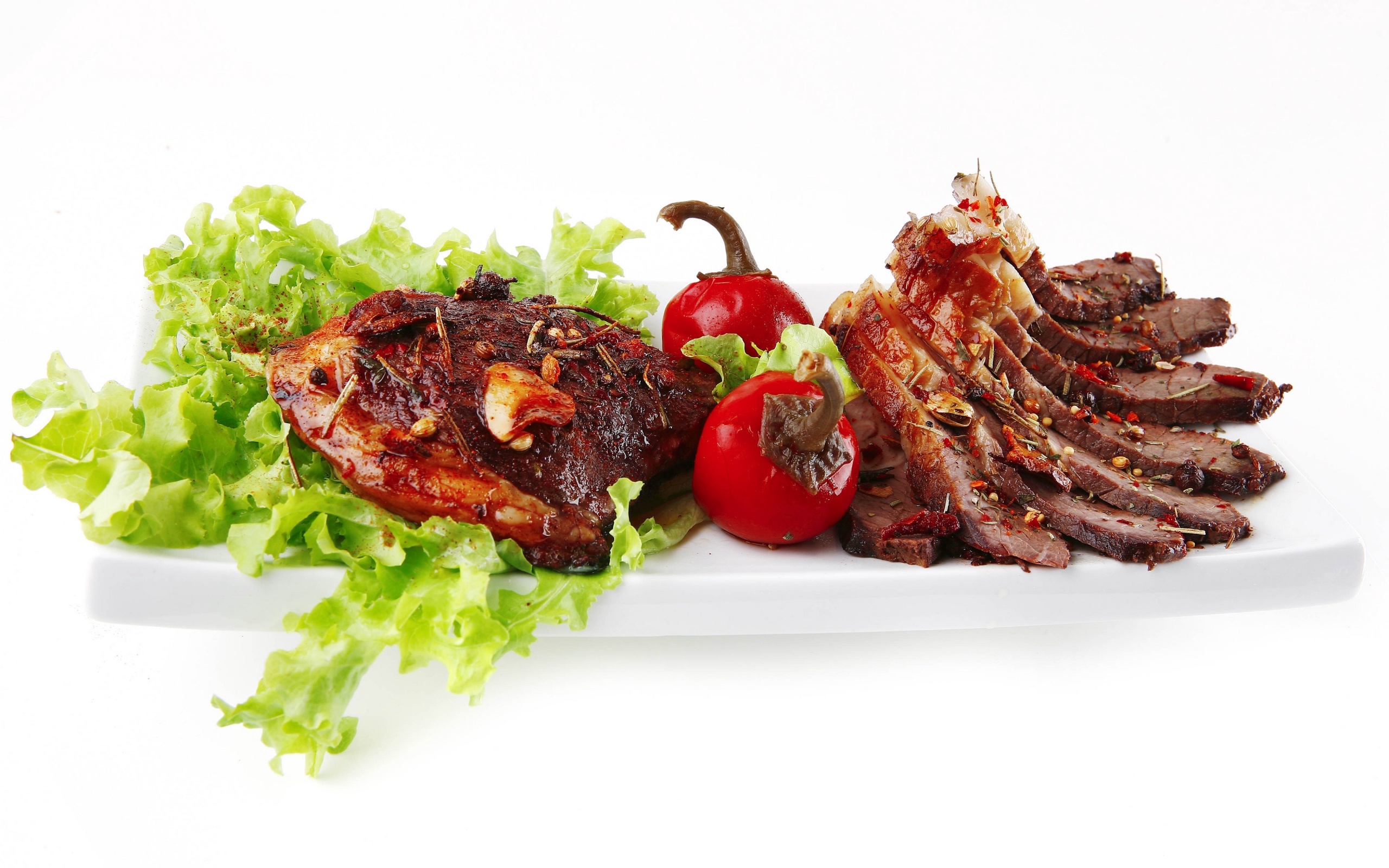 Мясо с листьями салата и красным перцем на белом фоне