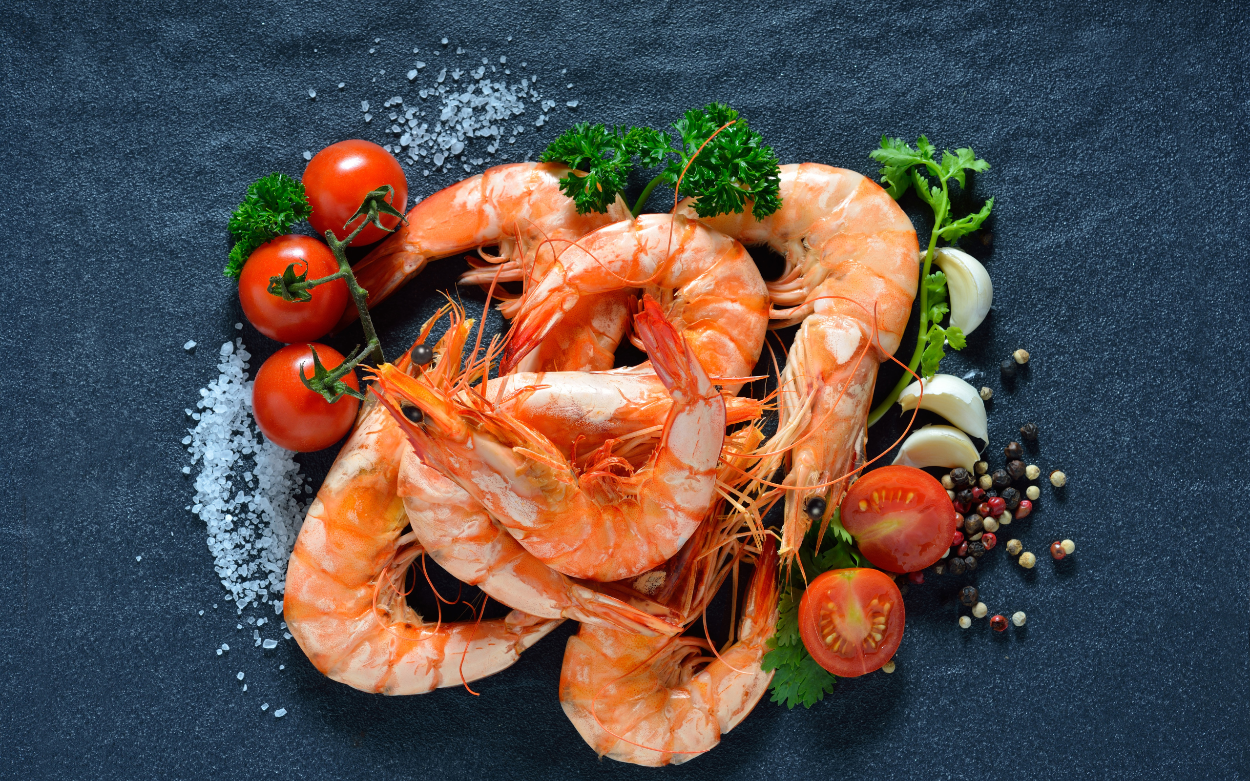 Вареные креветки на столе со специями и  помидорами 