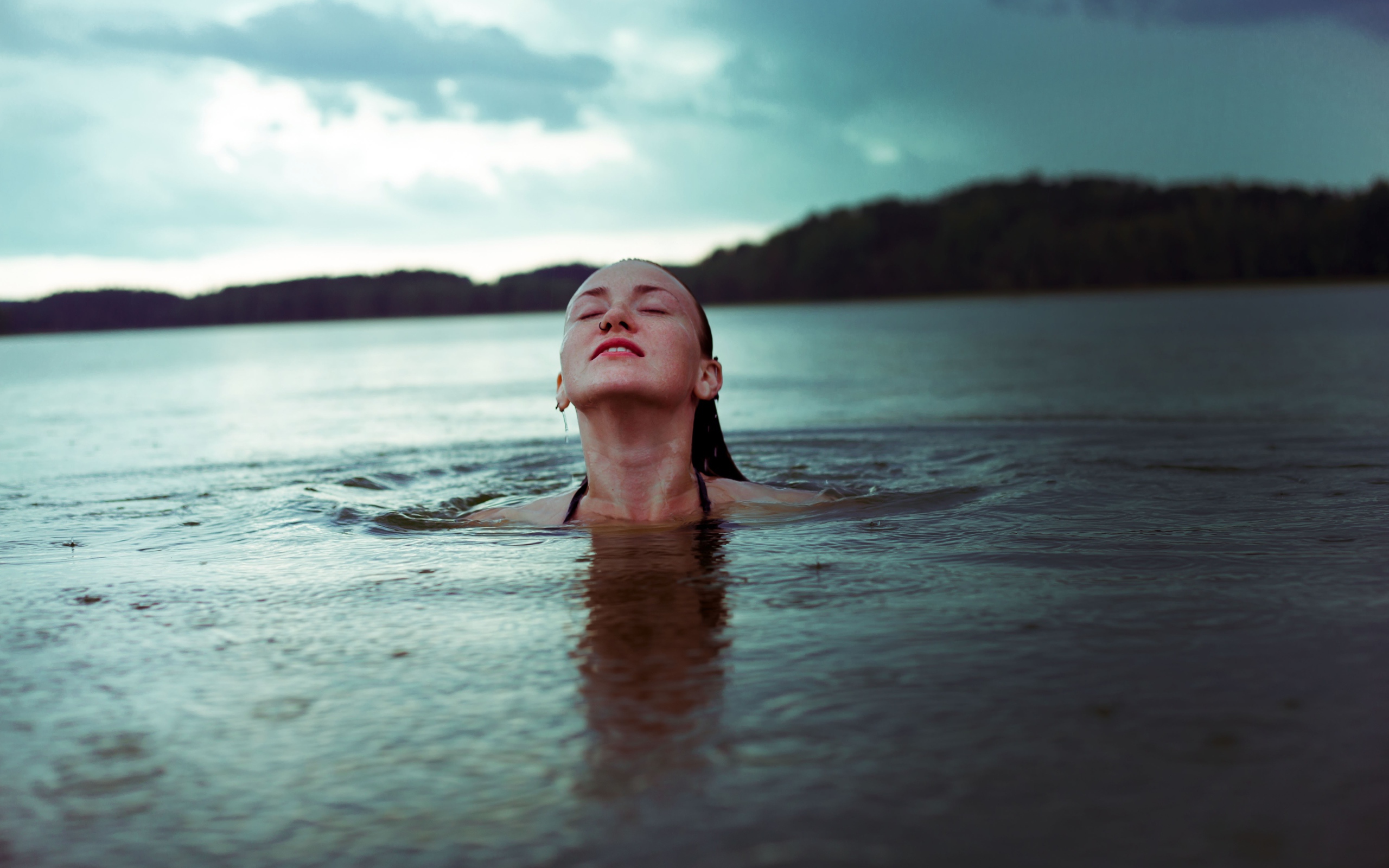 Молодая девушка купается в озере 