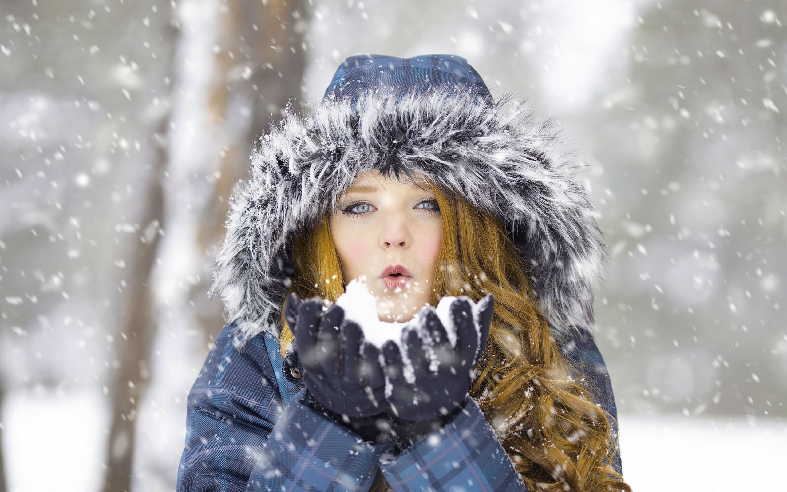 Красивая девушка в теплой куртке со снегом в руках