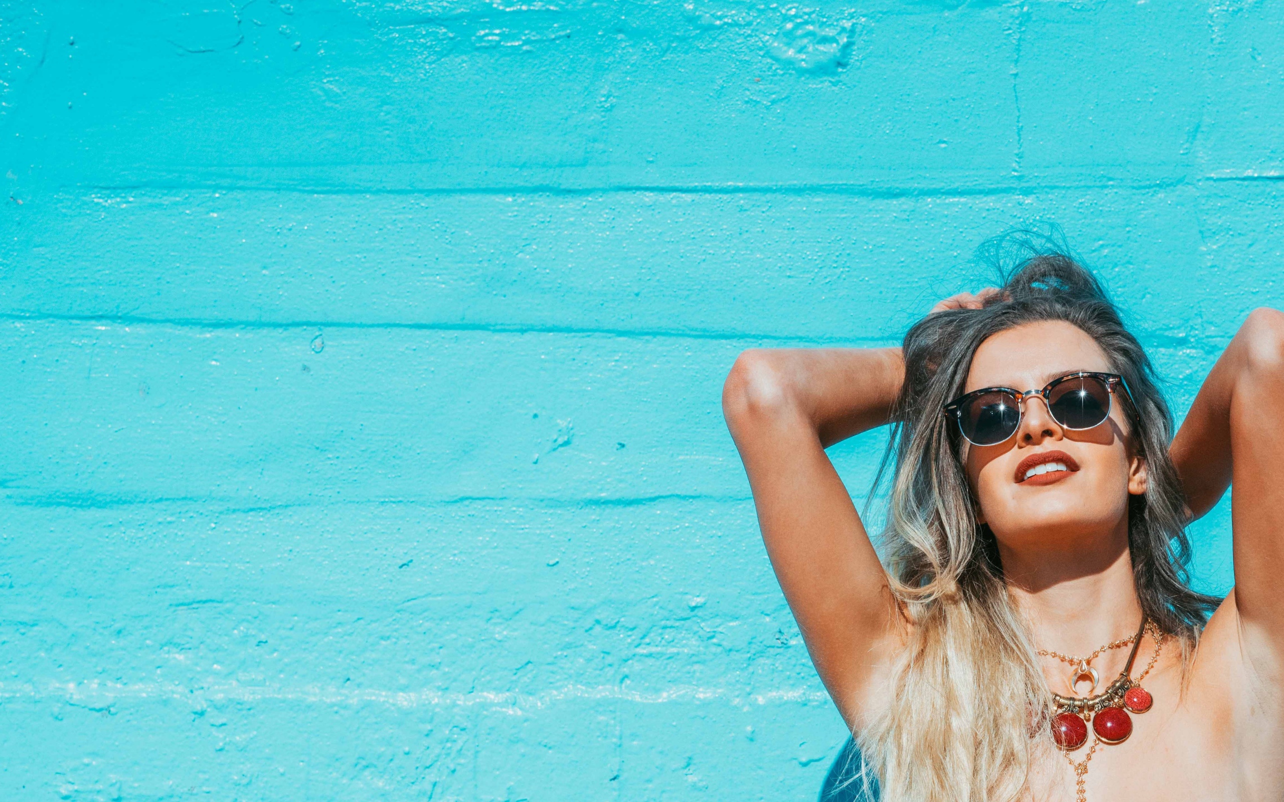 Красивая девушка в солнечных очках загорает на солнце летом