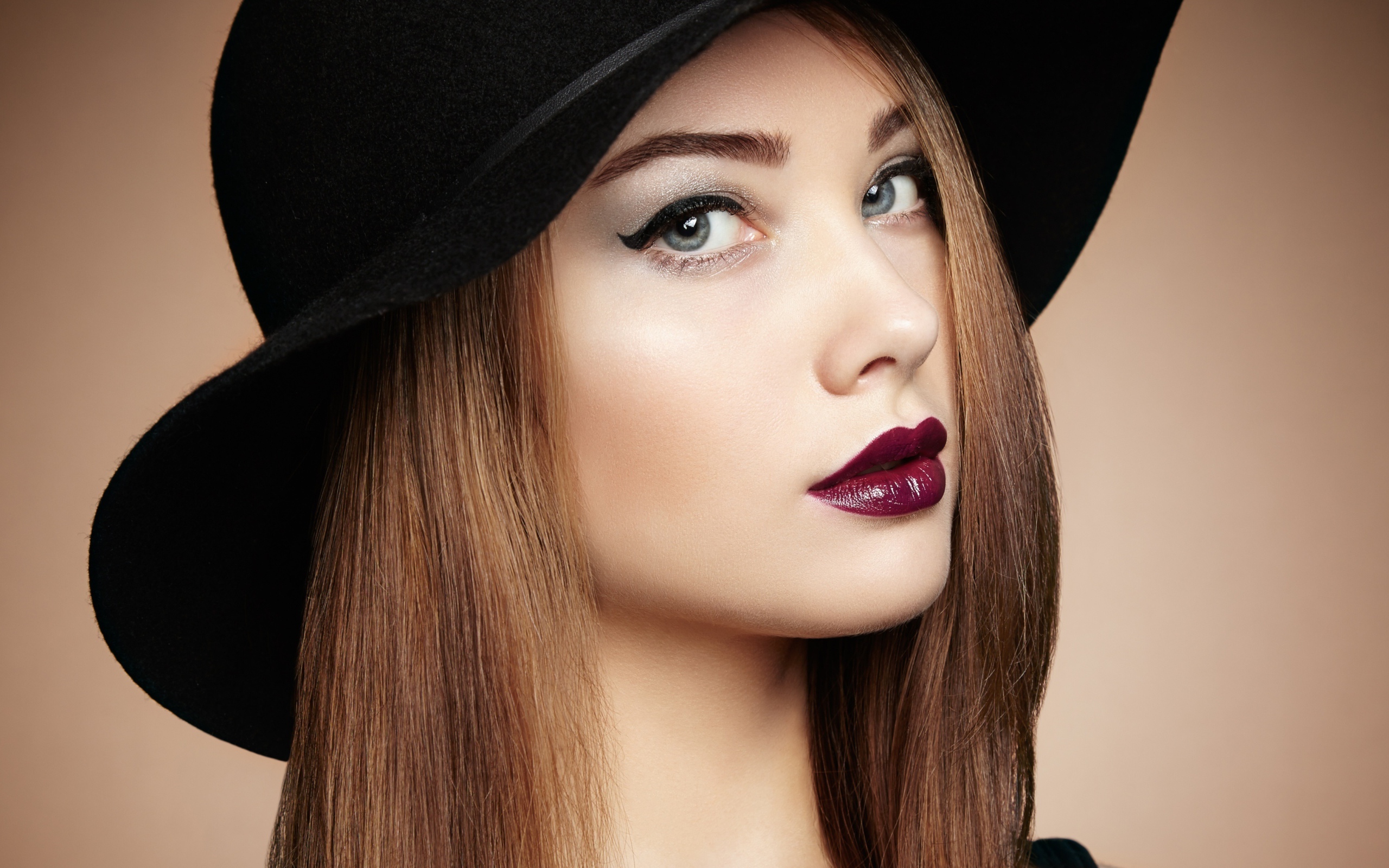 Красивая девушка с ярким макияжем в большой черной шляпе