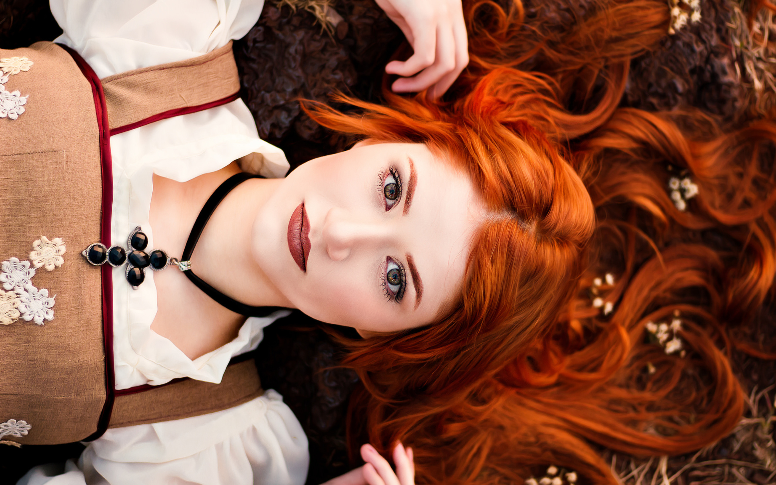 Красивая рыжеволосая девушка лежит на земле 