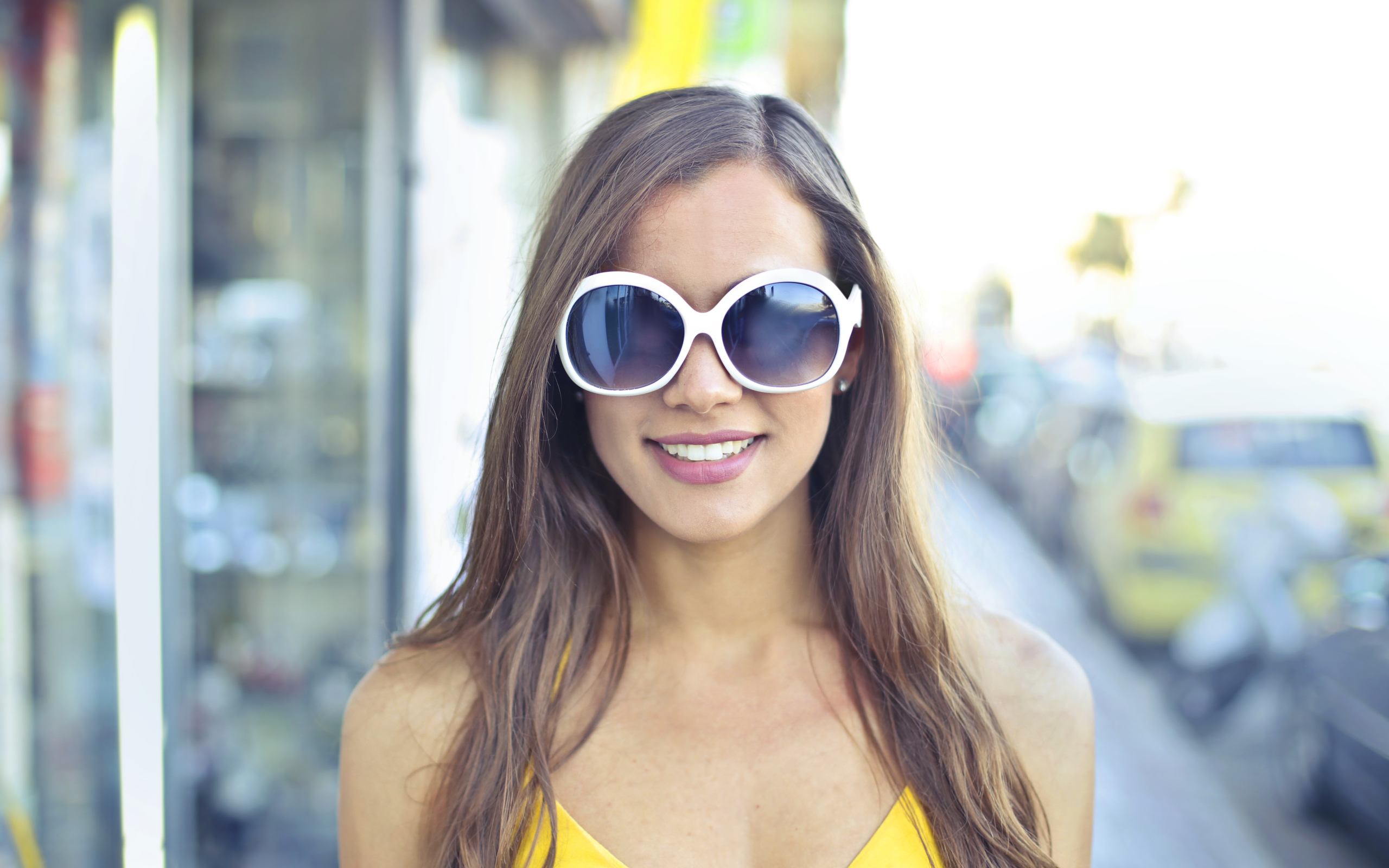 Улыбающаяся молодая девушка в солнечных очках 
