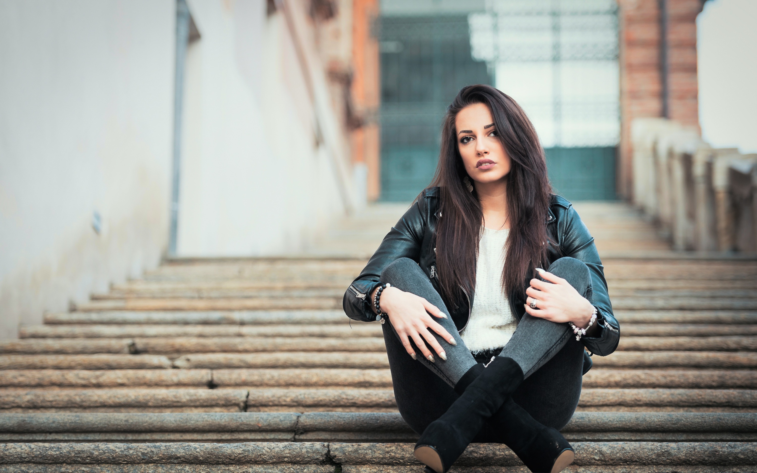 Молодая брюнетка сидит на ступеньках