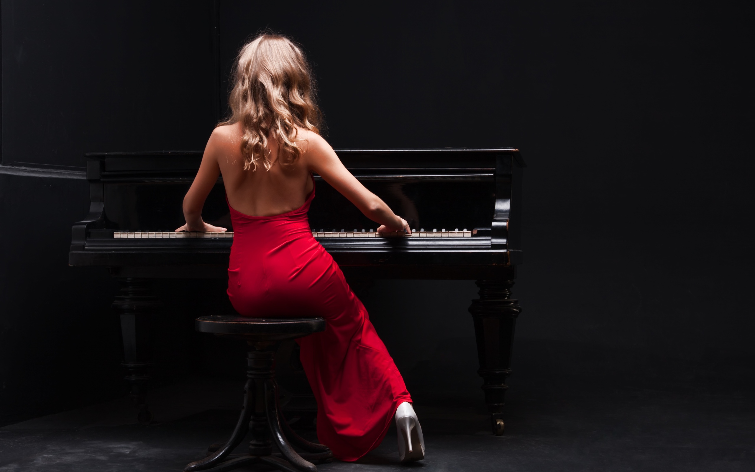 Молодая девушка в красном платье играет на пианино
