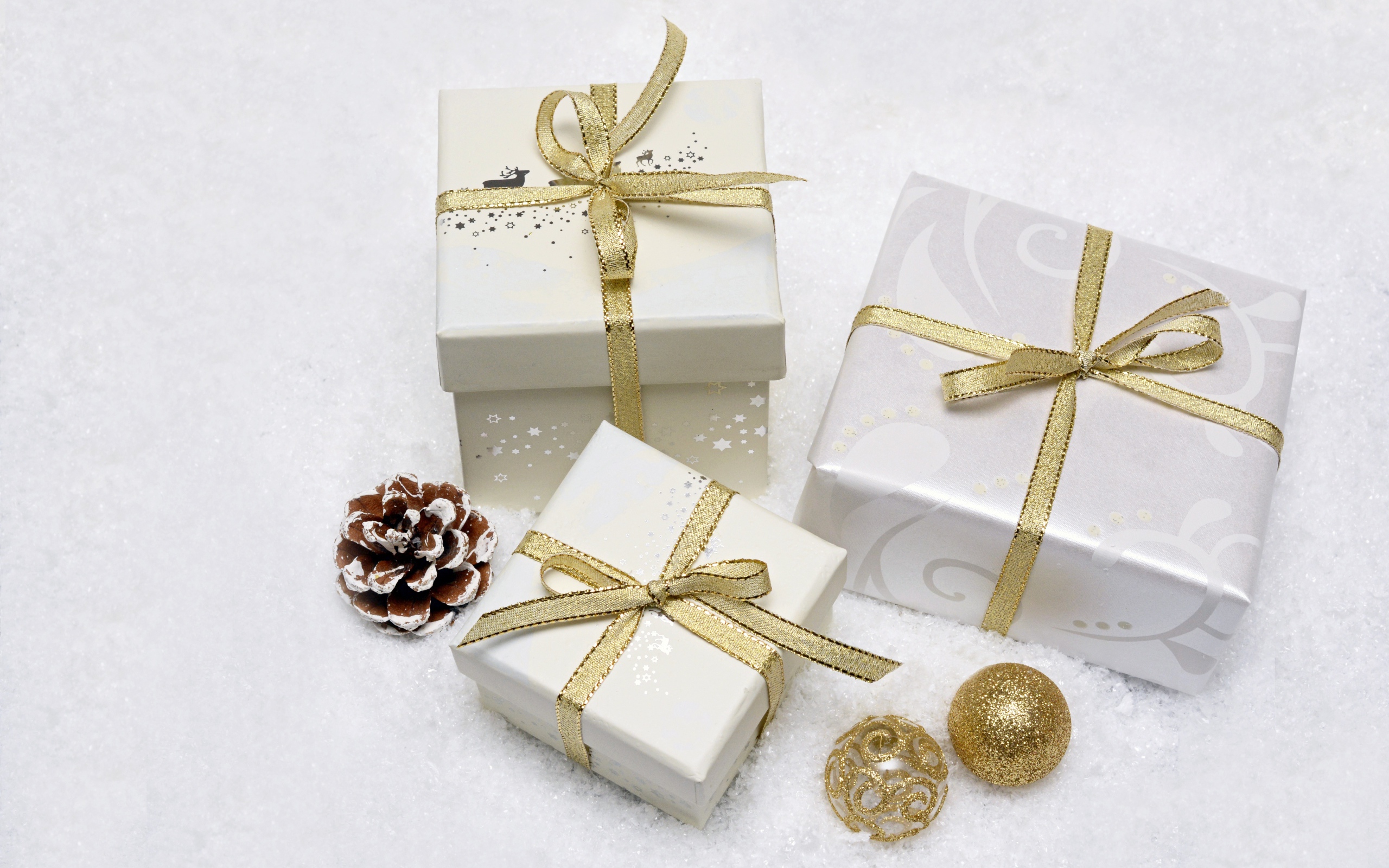 Три коробки с подарками с золотистыми бантами из ленты 