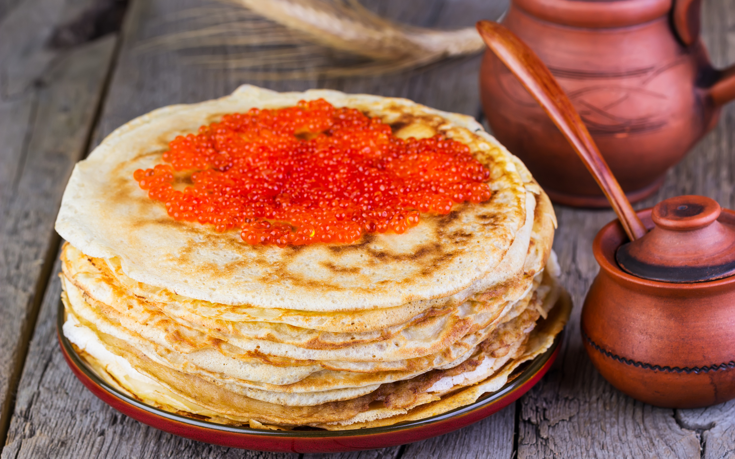 Стопка блинов с красной икрой на деревянном столе угощение на Масленицу