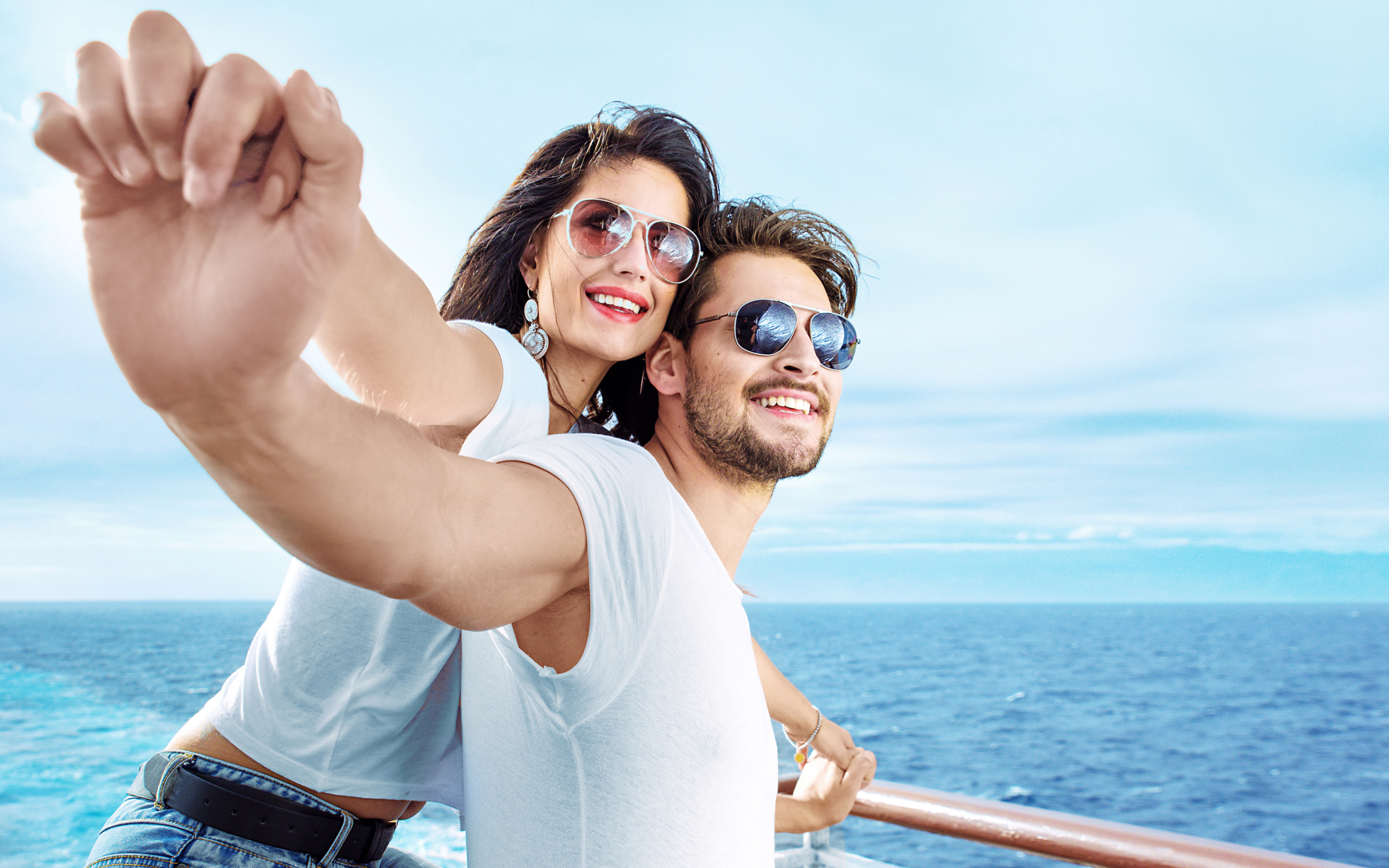 Влюбленная пара держится за руки на фоне моря