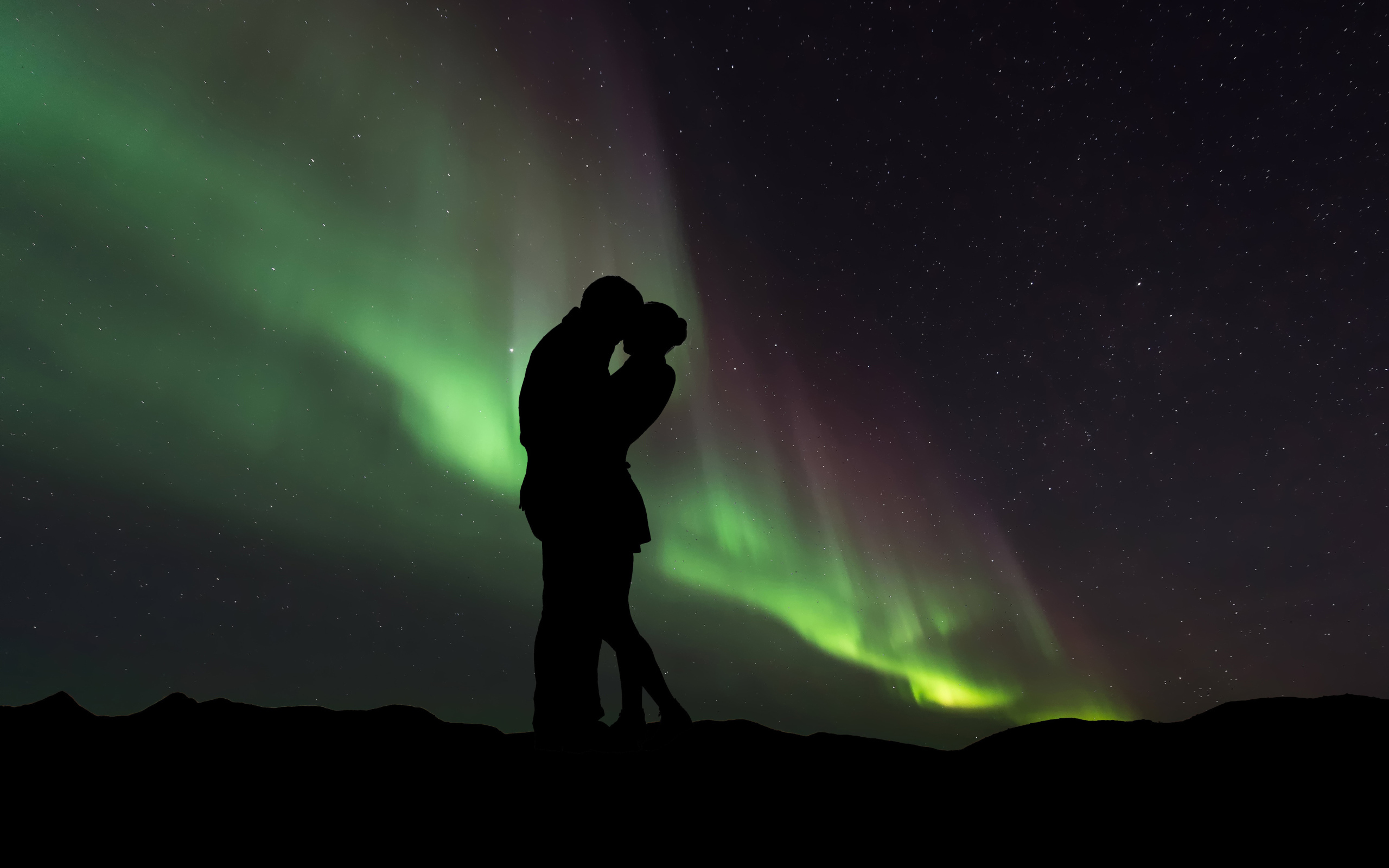 Силуэт влюбленной пары на фоне северного сияния 