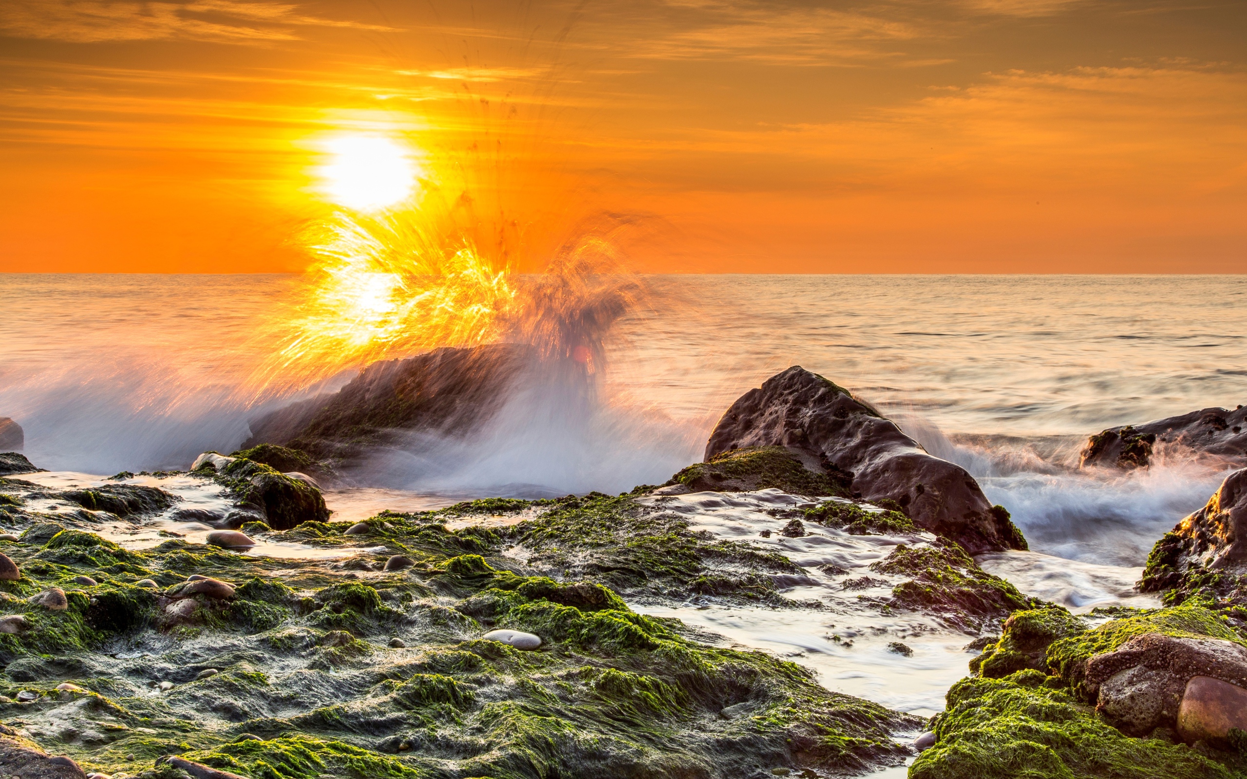 Бушующие волны в море бьются об камни на закате