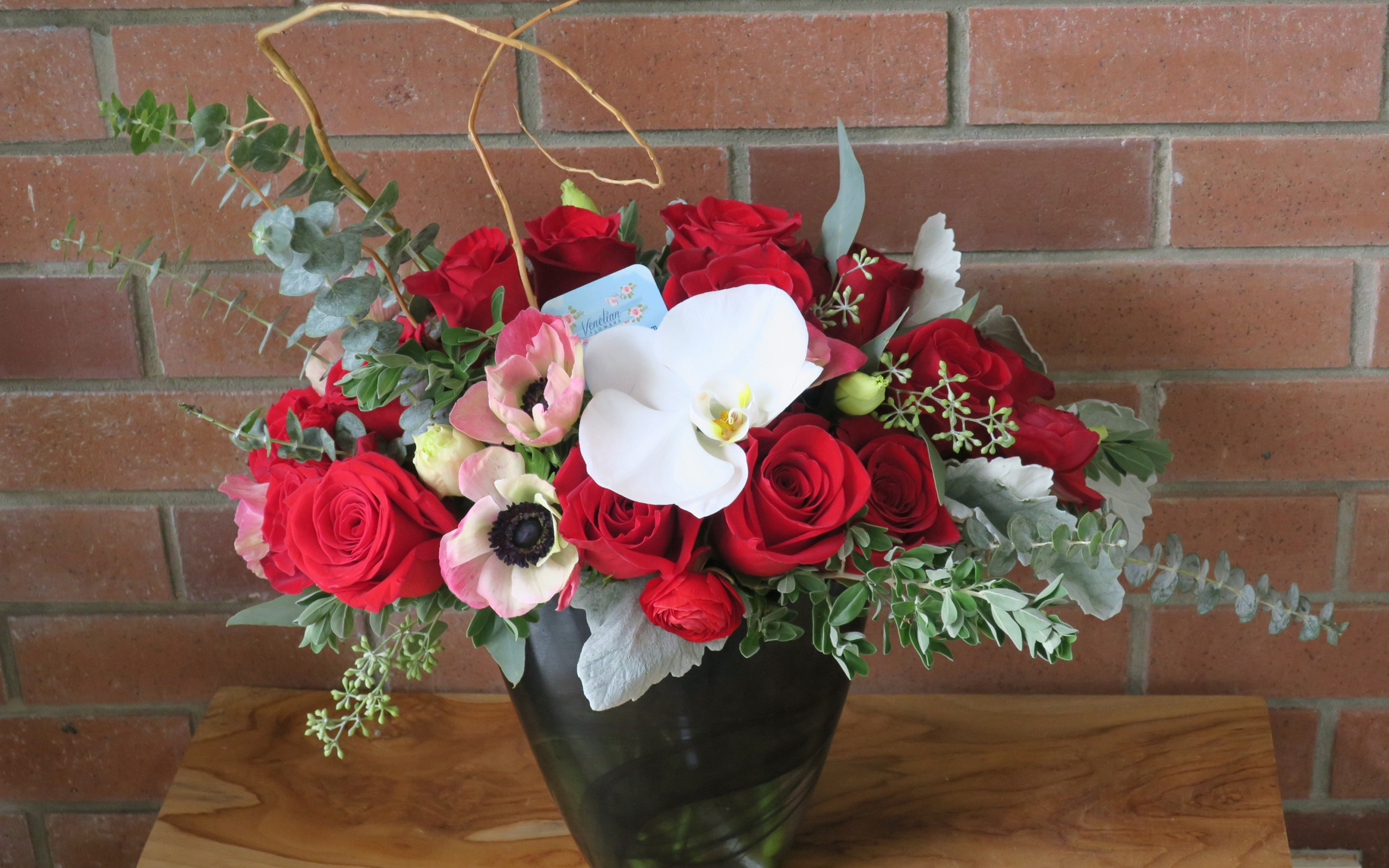 Букет с цветами анемоны, розы и орхидеи у стены 