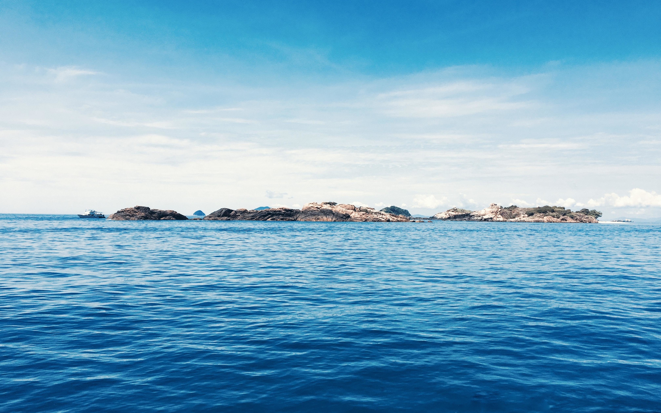 Спокойное синее море со скалами на горизонте