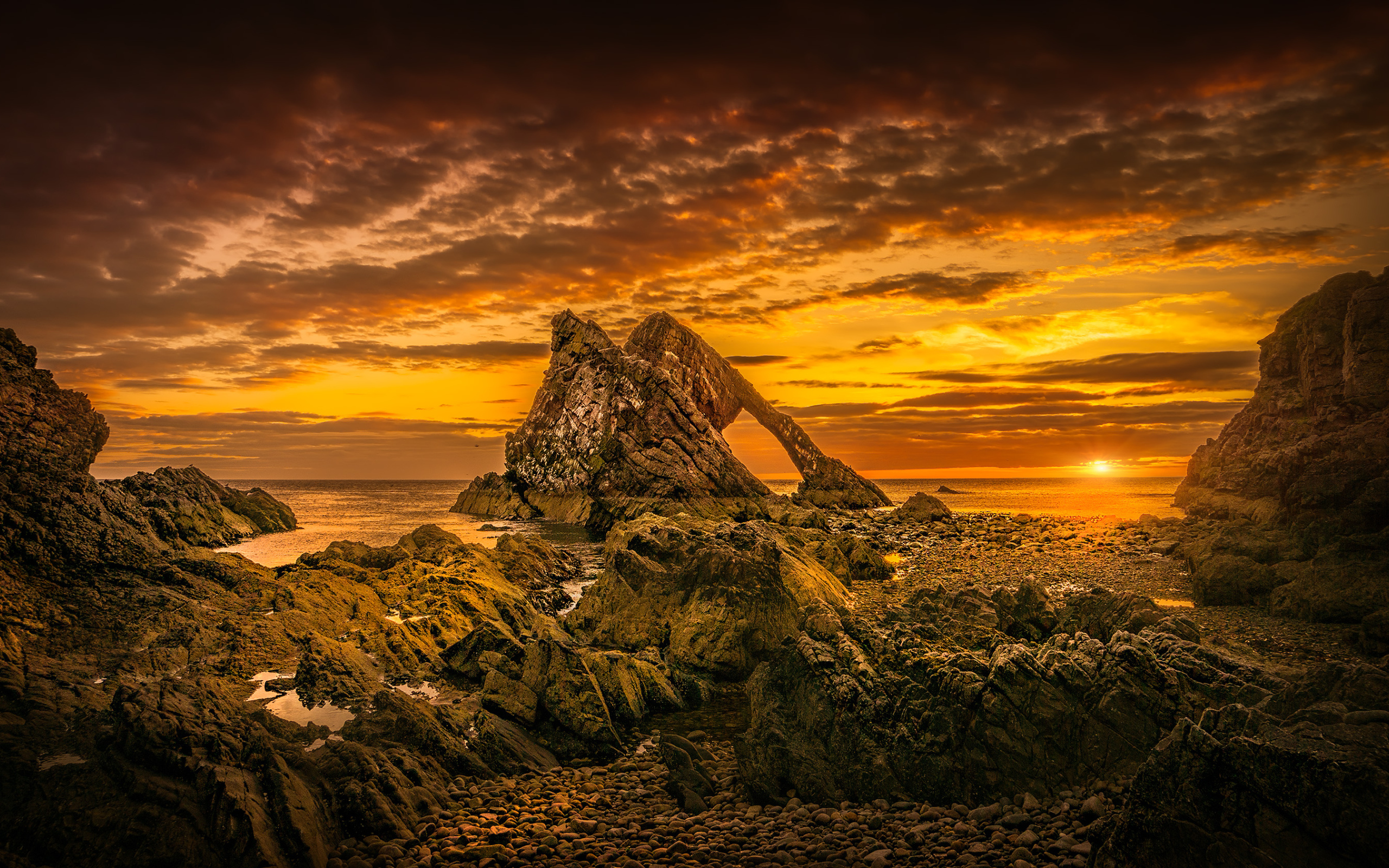 Скала в море на закате солнца под облачным небом